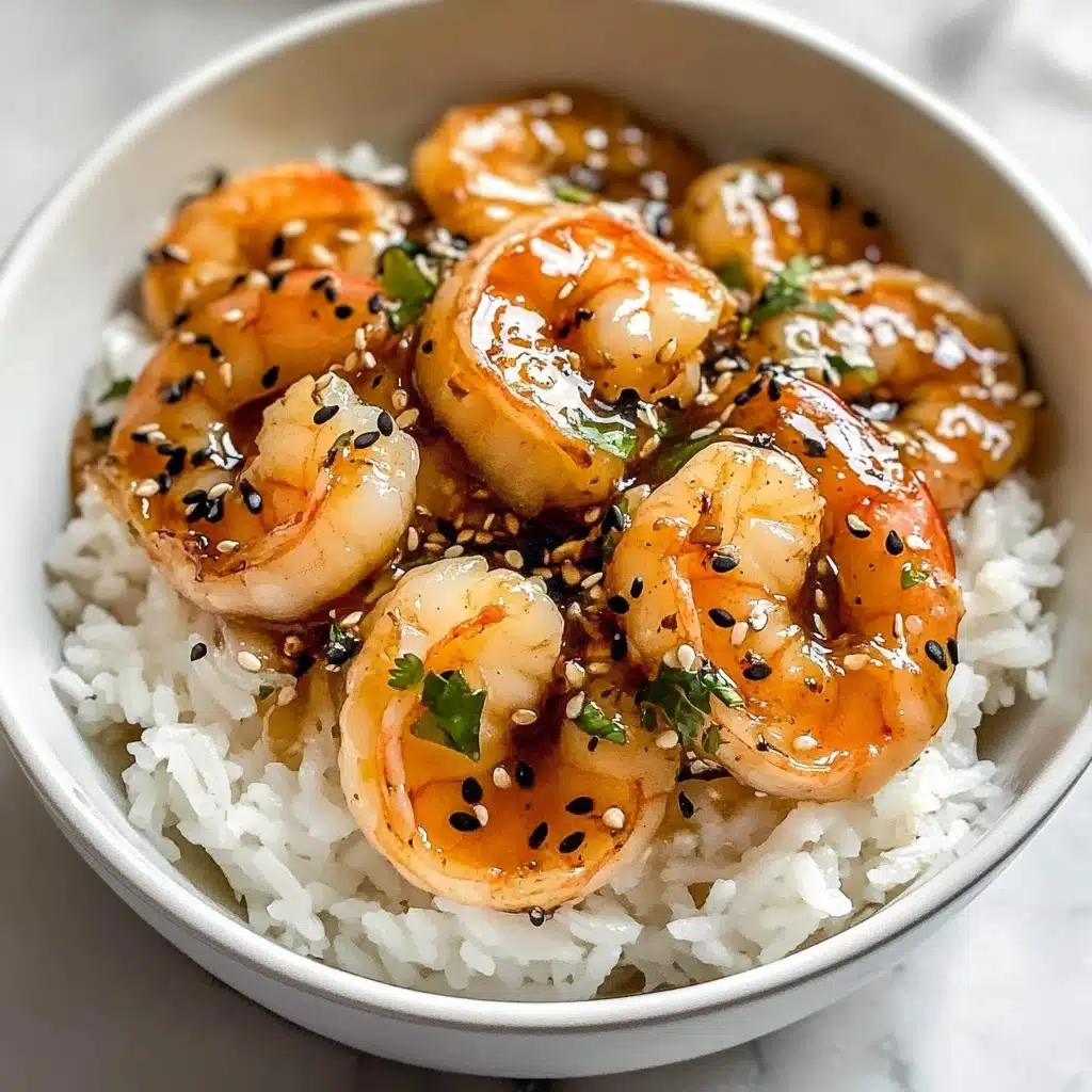 Ginger Garlic Sesame Shrimp, Asian-inspired shrimp stir-fry, quick shrimp dinner, flavorful shrimp recipe, easy seafood dinner A white bowl filled with a base layer of fluffy white rice topped with a layer of large cooked shrimp coated in a shiny, light brown sauce. The shrimp have a slightly orange color on the tail ends and are sprinkled with black and white sesame seeds and small chopped green herbs. The sauce pools slightly over the shrimp and rice, giving a glossy texture. The bowl sits on a white marbled surface.