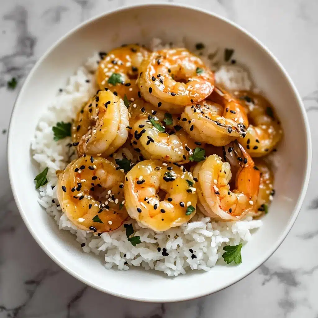 Ginger Garlic Sesame Shrimp, Asian-inspired shrimp stir-fry, quick shrimp dinner, flavorful shrimp recipe, easy seafood dinner A white bowl filled with a bed of white rice as the base layer, topped with several golden shrimp coated in a light orange sauce. The shrimp are garnished with small black sesame seeds and green parsley pieces scattered across the dish. The bowl is placed on a white marbled surface.