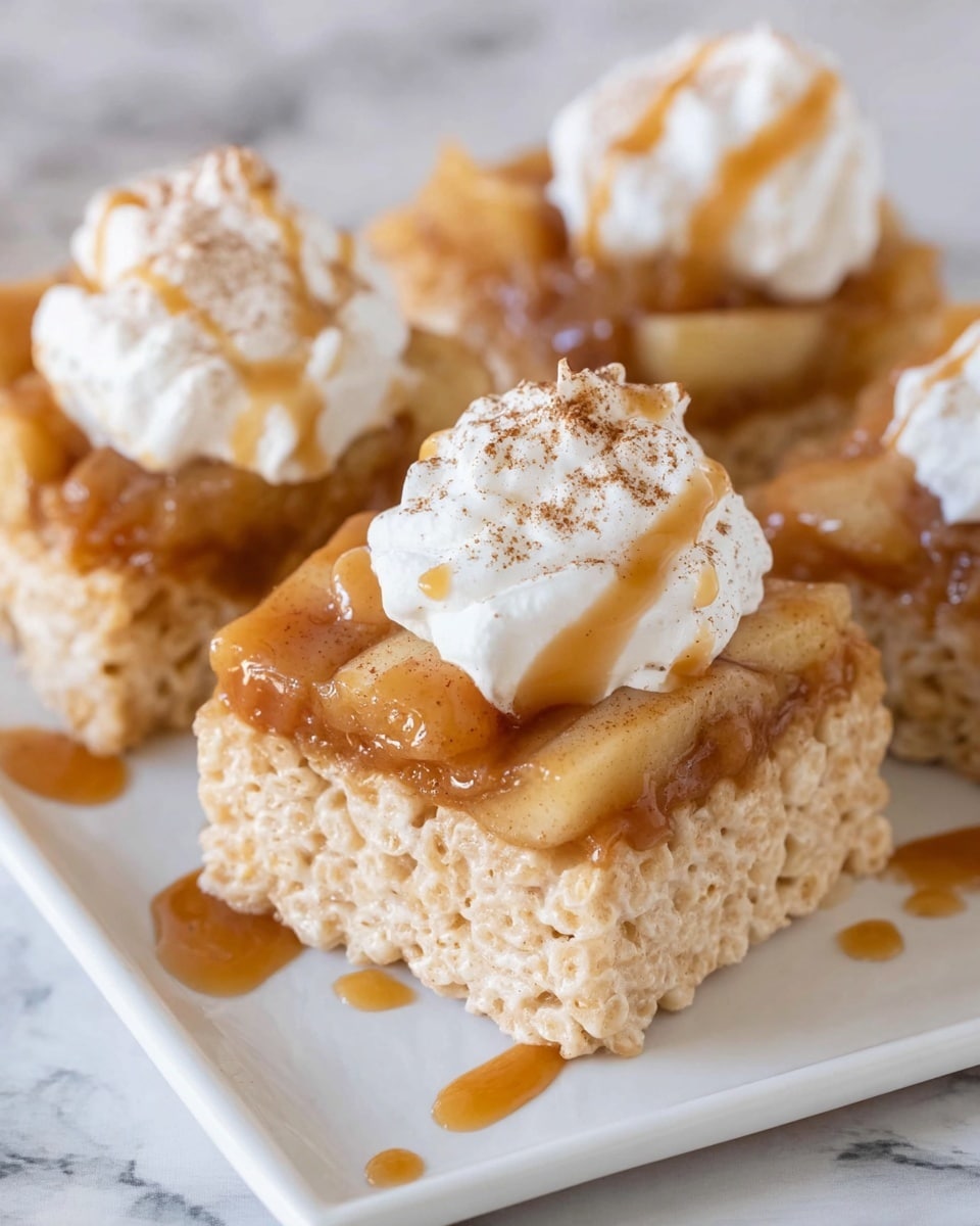 The image shows three square rice cereal treats on a white rectangular plate with a white marbled background. Each treat has three layers: the bottom layer is a golden rice cereal bar with a rough, puffy texture, the middle layer is a glossy caramel-colored apple topping with visible soft apple pieces, and the top layer is a dollop of white whipped cream sprinkled lightly with cinnamon powder and drizzled with caramel sauce. The caramel sauce also drips slightly onto the plate around the treats. Photo taken with an iphone --ar 4:5 --v 7