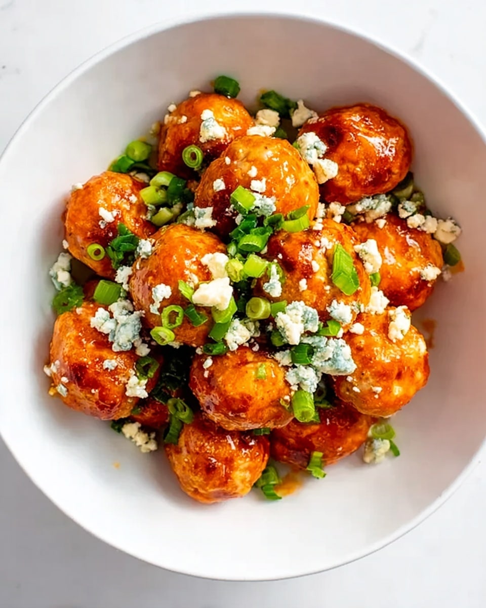 A white oval plate holds about fifteen round orange meatballs covered in a shiny sauce. They are topped with small white cheese crumbles and scattered light green chopped scallions. The plate sits on a white marbled surface with some green scallions spread around it. A silver fork lies near the plate's edge, and a corner of a blue bowl with white sauce and a striped cloth are visible in the background. photo taken with an iphone --ar 4:5 --v 7