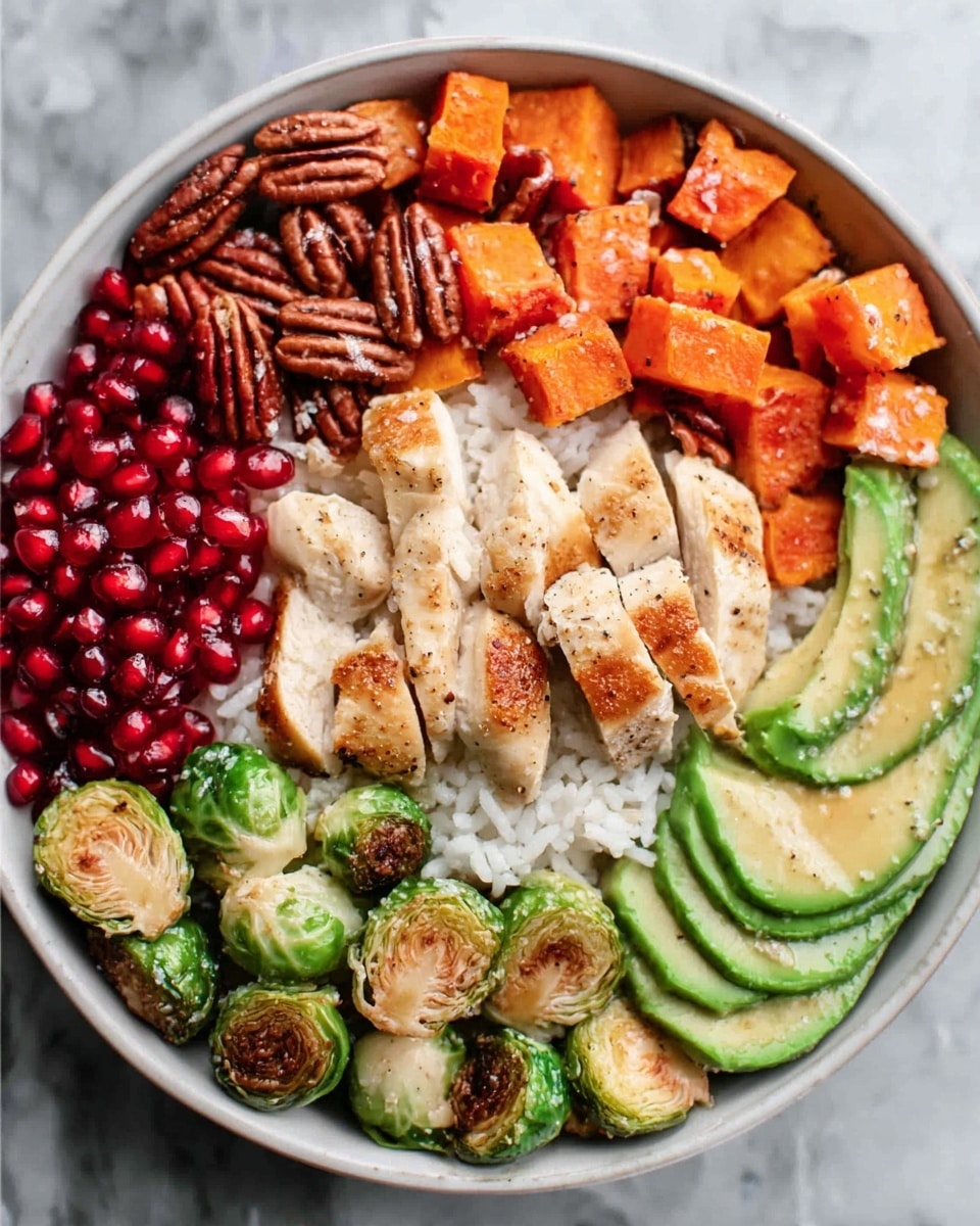 The dish in a white bowl is layered with white rice as the base, topped with bright red pomegranate seeds on one side. Next to it are light brown cooked pecans and roasted green Brussels sprouts. In the center are browned chicken strips with a slightly crispy texture and black pepper specks. On the right, there are cubed orange sweet potatoes and thin slices of green avocado. The bowl rests on a white marbled texture surface. photo taken with an iphone --ar 4:5 --v 7
