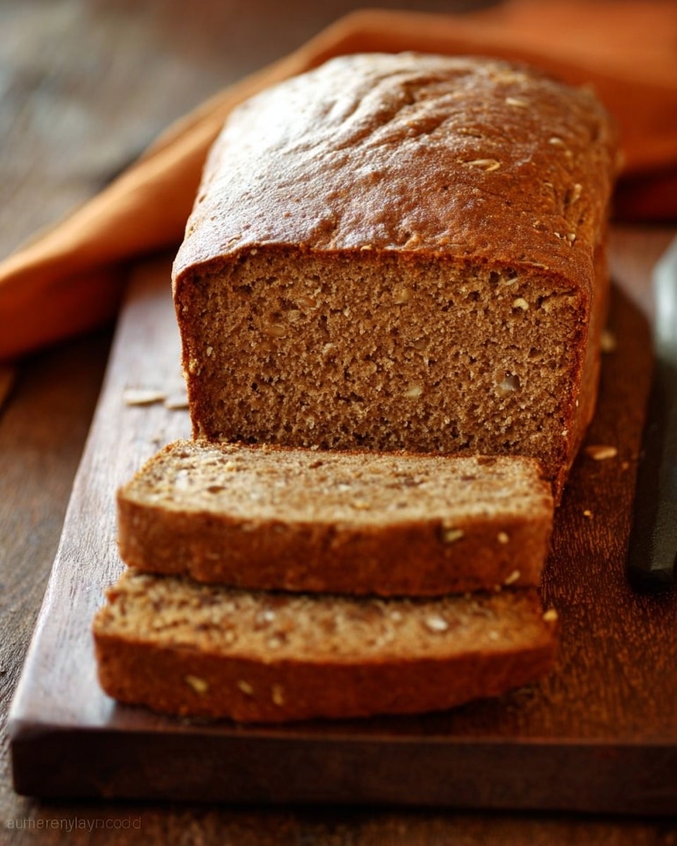 A close-up view of a single large loaf of bread sitting on a black wire rack, showing its golden-brown crust with a rough, slightly cracked texture on the top. The loaf is rectangular and thick, with a darker brown color on the sides. The background is a white marbled surface seen softly behind the wire rack. photo taken with an iphone --ar 4:5 --v 7