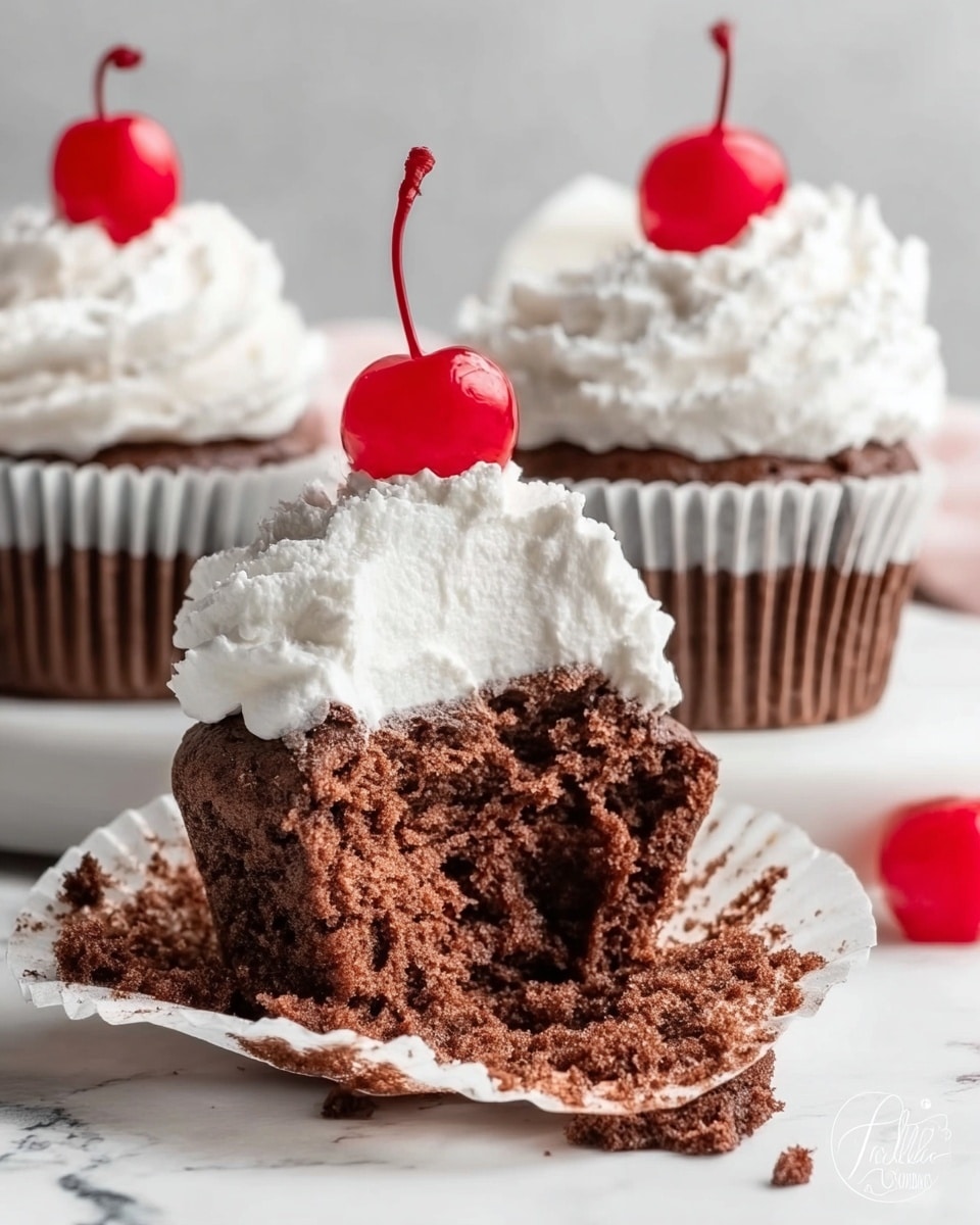 The image shows three chocolate cupcakes topped with thick, white whipped cream and a bright red cherry on each cupcake. Two cupcakes stand upright in the background, while one is broken in half and laid flat on a white paper liner in the front, showing the soft, fluffy, and dense chocolate cake inside. Some whipped cream spills over from the broken cupcake, and a cherry sits next to it on the white marbled surface. The colors in the image mainly include rich brown from the cake, bright white from the cream, and bright red from the cherries. The photo taken with an iphone --ar 4:5 --v 7