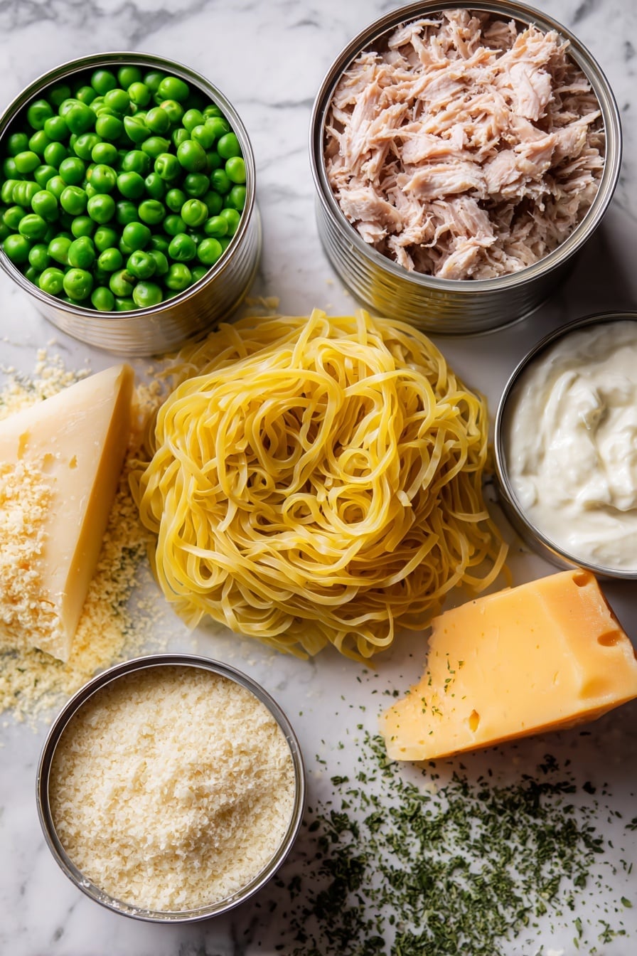 Flat lay of fresh yellow egg noodles coiled loosely, two shiny silver cans of tuna opened showing flaky light pink tuna, a small pile of bright green frozen peas glistening with frost, a wedge of sharp orange cheddar cheese with a slightly crumbly texture, a mound of creamy sour cream with a smooth surface, a handful of golden brown panko breadcrumbs with a rough texture, a small heap of pale beige grated parmesan cheese, and scattered dried parsley flakes in vibrant green, all arranged artfully to highlight their natural colors and textures, placed on white marbled surface, photo taken with an iphone --ar 2:3 --v 7 - Creamy Tuna Noodle Casserole, Tuna Noodle Casserole, Easy Tuna Casserole, Comfort Food Recipes, Weeknight Dinners