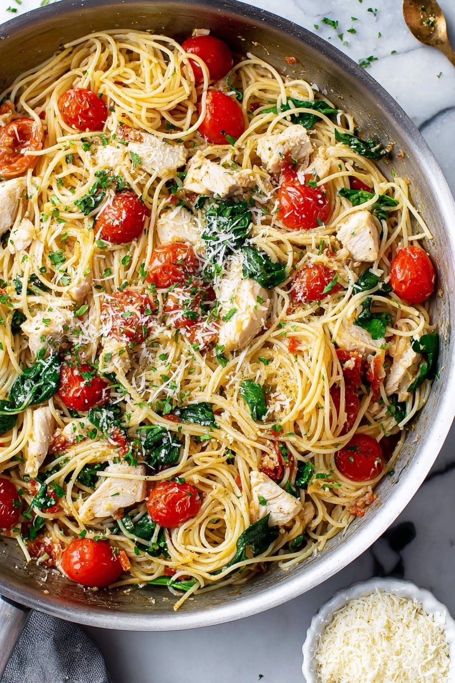 This image shows a pan filled with cooked thin spaghetti mixed with white chicken pieces, bright red cherry tomatoes cut in halves, and fresh green spinach leaves scattered throughout. The pasta looks soft and tangled, and there are small sprinkles of grated cheese and finely chopped green herbs on top. The pan sits on a white marbled surface, and near the bottom right corner, there is a small white bowl filled with more grated cheese. The whole dish looks fresh and colorful. photo taken with an iphone --ar 2:3 --v 7 - Creamy Chicken Scampi with Cherry Tomatoes and Spinach, Chicken Scampi, Easy Chicken Dinner, Fresh Tomato and Spinach Pasta, Weeknight Chicken Recipes