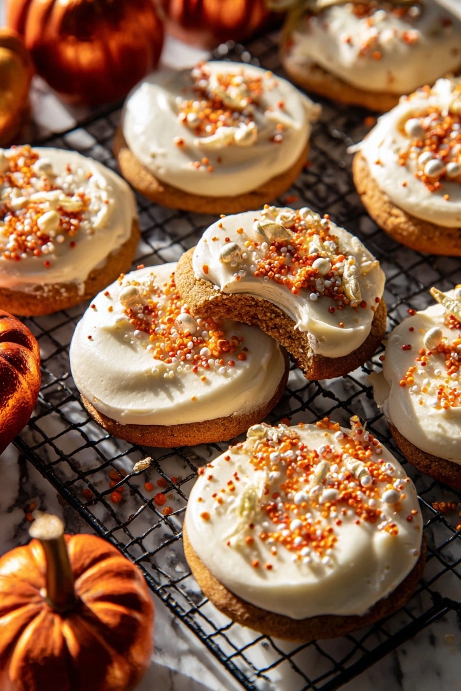 The image shows a group of round cookies, each with one thick, creamy white frosting layer on top. The frosting is smooth and spread evenly, decorated with small orange, white, and gold sprinkles scattered on the surface. One cookie is lifted slightly, showing the soft brown cookie base beneath the frosting. The cookies rest on a black wire cooling rack placed on a white marbled surface. Around the cookies, there are a few small, shiny dark orange mini pumpkins adding a warm autumn feel. Bright sunlight shines on the scene, creating strong shadows and highlighting the textures. Photo taken with an iphone --ar 2:3 --v 7 - Frosted Soft Pumpkin Sugar Cookies, pumpkin spice sugar cookies, fall cookies with cream cheese frosting, cozy pumpkin dessert, soft pumpkin cookie recipe