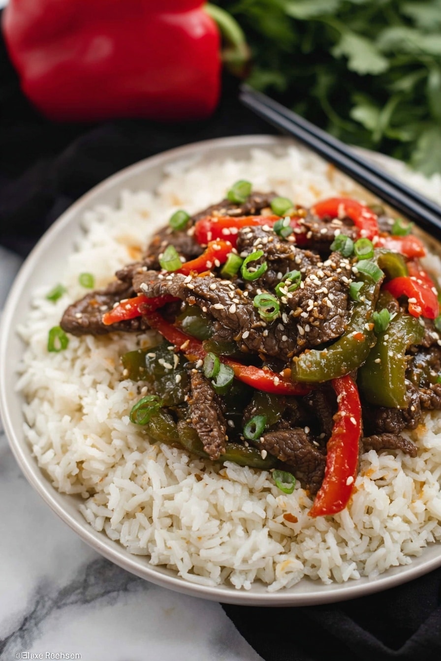 The dish shows three layers on a black plate: the bottom layer is a bed of fluffy white rice with a soft texture, the middle layer has bright green and red cooked bell peppers that look tender and shiny, and the top layer is dark brown strips of cooked beef covered with white sesame seeds and small pieces of green onion scattered on top. The background is a white marbled texture with a pair of dark chopsticks resting near the plate. photo taken with an iphone --ar 2:3 --v 7 - Crockpot Pepper Steak, Slow Cooker Beef and Bell Pepper, Easy Crockpot Beef Stir Fry, Savory Pepper Steak Recipe, Tender Beef Crockpot Dinner
