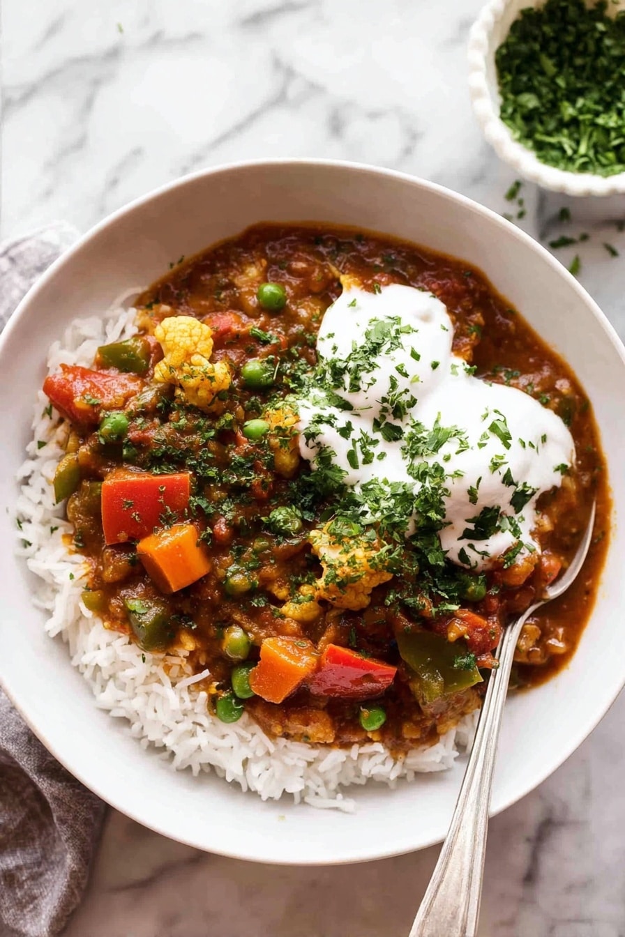 A white bowl filled with a base layer of white rice topped with a colorful vegetable curry. The curry has pieces of orange carrots, bright green peas, red bell peppers, and bits of cauliflower all mixed in a rich reddish-brown sauce. On top of the curry, there are two dollops of smooth white yogurt sprinkled with chopped green herbs. A silver spoon rests inside the bowl on the right side. The bowl is placed on a white marbled surface, and in the background, there is a small white bowl filled with chopped green herbs. photo taken with an iphone --ar 2:3 --v 7 - Vegetable Curry, Vegetable Curry Recipe, Vegan Vegetable Curry, Easy Vegetable Curry, Healthy Curry Dish