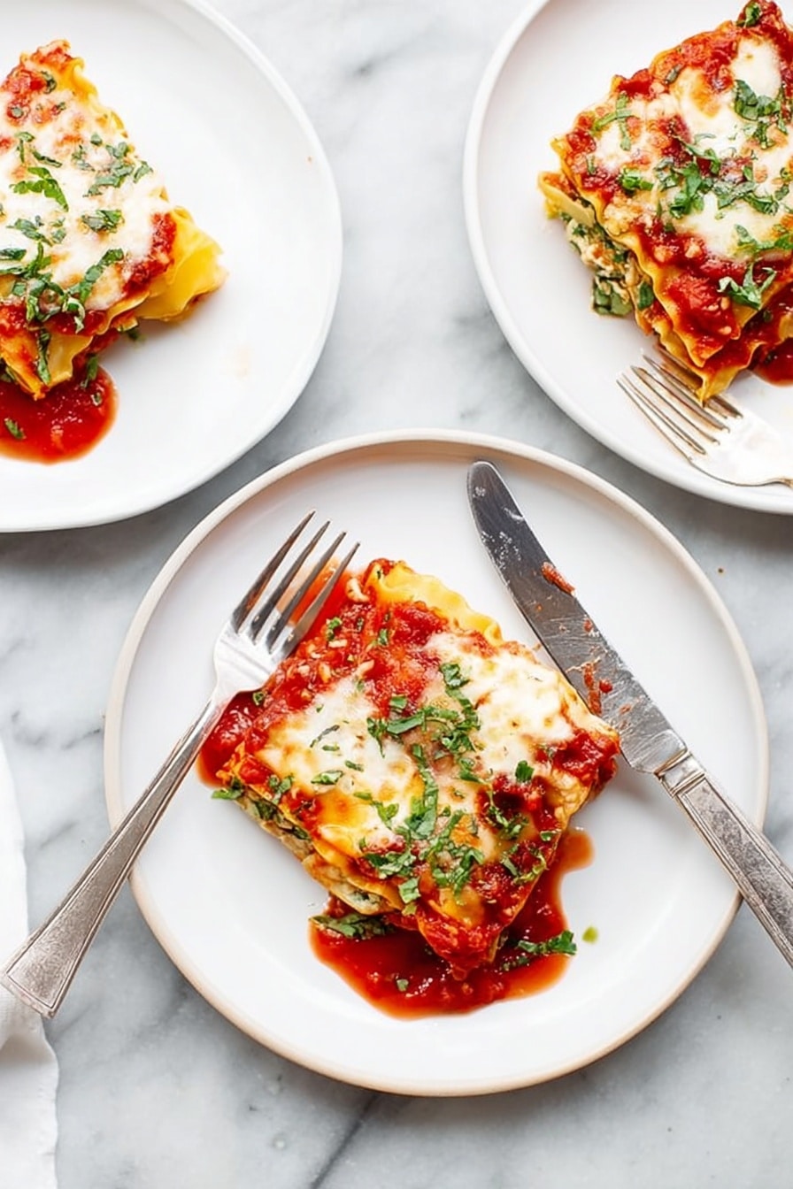 There are three white plates on a white marbled surface, each with a square piece of lasagna. Each lasagna piece has visible layers: a red tomato sauce at the bottom, a yellow pasta sheet, white cheese melted on top with some browned spots, and green herbs sprinkled over all. One plate in the middle has a fork and a knife resting on the edges, the knife laying diagonally across the plate. The tomato sauce slightly spreads around each lasagna piece, adding a bright red contrast to the white plates and light background. Photo taken with an iphone --ar 2:3 --v 7 - Spinach Lasagna Roll-Ups, spinach lasagna, cheesy spinach pasta, healthy lasagna alternatives, easy spinach roll-ups