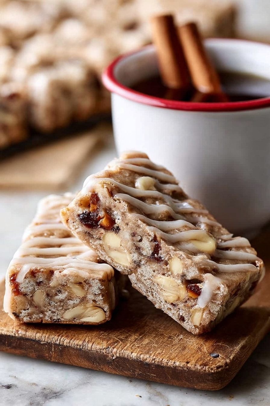 The image shows two triangular bars leaning against each other on a wooden board with a cinnamon stick nearby. Each bar has a thick, light brown base with a slightly crumbly texture, filled with visible chunks of nuts and possibly dried fruit, giving darker brown and creamy white spots inside. The bars are drizzled with a light tan glaze in thin lines across the top and sides. Next to the bars is a white cup with a red rim containing a dark liquid and two cinnamon sticks inside. The background is blurred but shows more bars on a white marbled surface. photo taken with an iphone --ar 2:3 --v 7 - Brown Butter Apple Blondies with Cinnamon Maple Glaze, fall dessert recipes, apple blondie recipes, cozy autumn desserts, easy apple blondies