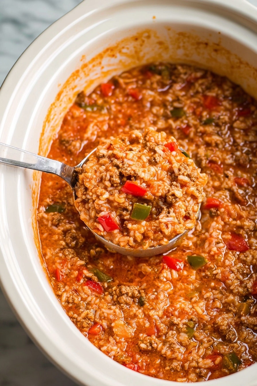 A white bowl filled with thick soup showing three main layers: the top layer has brown, crumbled cooked meat chunks, the middle layer contains soft rice grains mixed in a red tomato-based broth with visible small pieces of green and red bell peppers, and the bottom layer is the same dense, orange-red liquid base. The soup looks hearty and textured, with a spoon partially visible inside the bowl. The background has a white marbled texture, and a modern kitchen appliance is partially seen behind the bowl. photo taken with an iphone --ar 2:3 --v 7 - Slow Cooker Stuffed Pepper Soup, stuffed pepper soup recipe, easy slow cooker soup, hearty stuffed pepper dish, comforting dinner ideas
