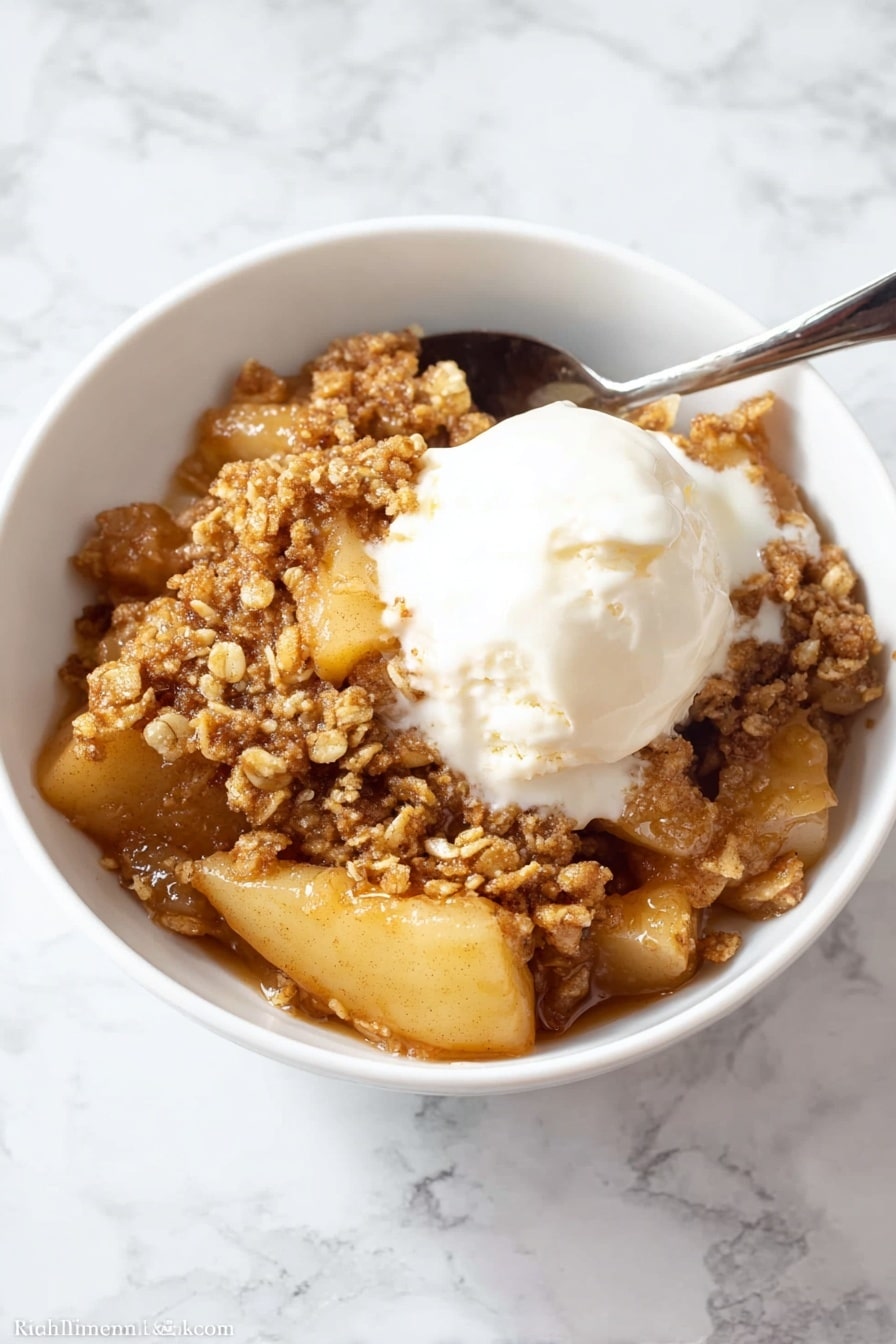 A close-up view of a white bowl filled with a warm apple dessert that has three main layers: a soft layer of sliced cooked apples with a light golden color on the bottom and middle, covered by a thick, sticky caramel sauce that gives a shiny, wet look, and topped with a crumbly, brown oat topping that looks crunchy with small clusters scattered unevenly on top. The dish looks moist and inviting, with the caramel sauce slightly dripping between the apple slices and crumbs. The white bowl sits against a white marbled surface. Photo taken with an iphone --ar 2:3 --v 7 - Healthy Apple Crisp, healthy apple crisp, healthy apple crisp dessert, wholesome apple crisp recipe, nutritious apple crisp