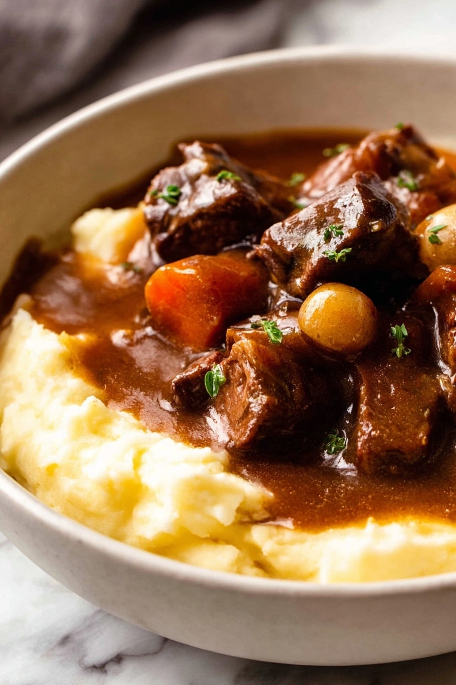 A white bowl filled with two layers: the bottom layer is smooth, creamy mashed potatoes in a light yellow color, and the top layer is a rich, dark brown stew with chunks of tender meat, whole small onions, and thick slices of carrots, all coated in a shiny gravy. The stew slightly spills over the mashed potatoes, garnished with small sprinkles of green herbs. The bowl is placed on a white marbled surface with a folded cloth and a glass of red wine slightly visible in the background along with a detailed old-fashioned spoon in front of the bowl. Photo taken with an iphone --ar 2:3 --v 7 - Beef Bourguignon, Beef Burgundy, French beef stew, hearty beef recipes, classic French dishes