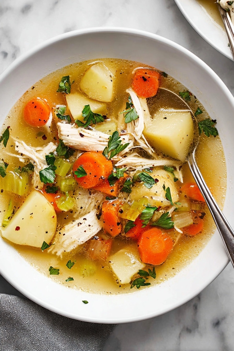 The image shows a white plate filled with clear chicken soup that has a golden broth base. Inside the soup, there are several layers: large pieces of white shredded chicken, sliced orange carrots, light beige potato slices, and sections of green celery. Scattered on top are fresh green parsley leaves and small black pepper bits. A silver spoon is partially dipped into the soup on the right side of the plate, resting against the edge. The plate is placed on a white marbled surface, with a grey cloth partially visible at the bottom left corner. photo taken with an iphone --ar 2:3 --v 7 - Ultimate Chicken Soup, Chicken Soup Recipe, Cozy Chicken Soup, Hearty Chicken Soup, Homemade Chicken Soup