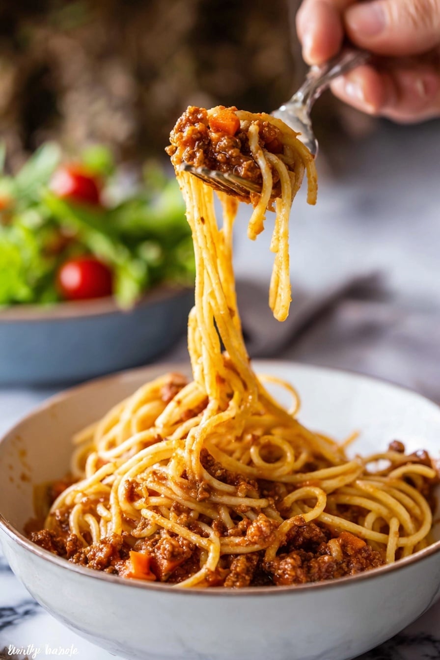 A close-up image shows a woman's hand holding a fork and spoon lifting a twirl of spaghetti from a white bowl filled with spaghetti bolognese. The spaghetti's long, thin yellow noodles are covered in a chunky, reddish-brown tomato sauce with visible bits of carrots and minced meat. The sauce coats the bottom layer of the bowl, creating a textured base under the lifted pasta. In the background, a blurred bowl of green salad with cherry tomatoes sits on a white marbled surface. The image focuses on the pasta being lifted, highlighting the sauce's texture and pasta's smooth strands. Photo taken with an iphone --ar 2:3 --v 7 - Slow Cooker Bolognese Sauce, easy Italian pasta sauce, hearty slow cooker dinner, flavorful Bolognese recipe, simple ground meat sauce