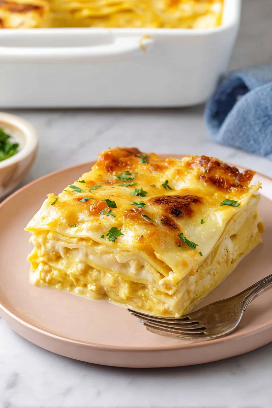 A square piece of lasagna with three visible layers is placed on a pale pink plate on a white marbled surface. The top layer is covered with melted golden-yellow cheese, sprinkled with fresh green herbs. Beneath, you can see creamy yellow sauce mixed with soft white pasta sheets and some herbs. In the background, a white baking dish with a golden top edge of more lasagna and a silver fork resting on the plate accompany the serving. photo taken with an iphone --ar 2:3 --v 7 - Butternut Squash Lasagna, healthy vegetarian lasagna, fall comfort food recipes, easy butternut squash dinner, cheesy vegetable lasagna
