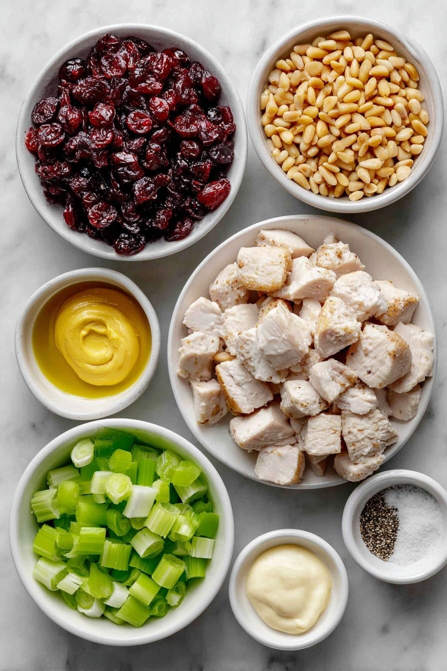 Flat lay of cooked chicken breast chopped into bite-sized pieces, a sliced celery stalk with bright green ribs, thinly sliced green onions showing white and green sections, a small white bowl filled with glossy sweet dried cranberries, a small white bowl containing toasted golden pine nuts, a small white bowl of creamy pale mayonnaise, a small white bowl holding smooth Dijon mustard, a small white bowl with coarse salt crystals, and a small white bowl with freshly ground black pepper placed on a clean white marble surface, soft natural light, photo taken with an iPhone, professional food photography style, fresh ingredients, white ceramic bowls, no bottles, no duplicates, no utensils, no packaging --ar 2:3 --v 7 --p awthu7i m7354615311229779997 - Cranberry Chicken Salad, Cranberry Chicken Salad Recipe, Easy Chicken Salad with Cranberries, Healthy Cranberry Chicken Salad, Refreshing Chicken Salad
