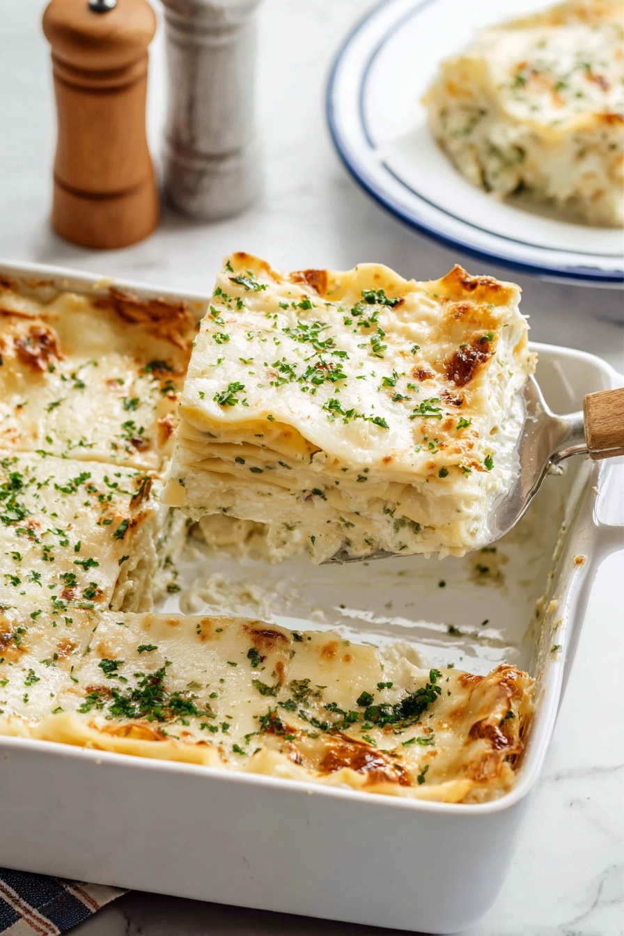 The image shows a white baking dish filled with a six-layer lasagna. Each layer consists of creamy white sauce and pasta sheets with soft, textured edges. The top layer is covered with melted white cheese sprinkled with finely chopped green herbs. The lasagna has a golden-brown crust on some edges. A metal spatula with a wooden handle is placed inside the dish, lifting one square piece from the corner. In the background, a slice of lasagna sits on a white plate with blue trim on a white marbled surface, with a blurred salt and pepper shaker set partly visible. Photo taken with an iphone --ar 2:3 --v 7 - Creamy Chicken Boursin Alfredo Lasagna, Chicken Boursin Alfredo Lasagna, Creamy Chicken Lasagna with Boursin, Boursin Chicken Alfredo Pasta, Easy Chicken Boursin Lasagna