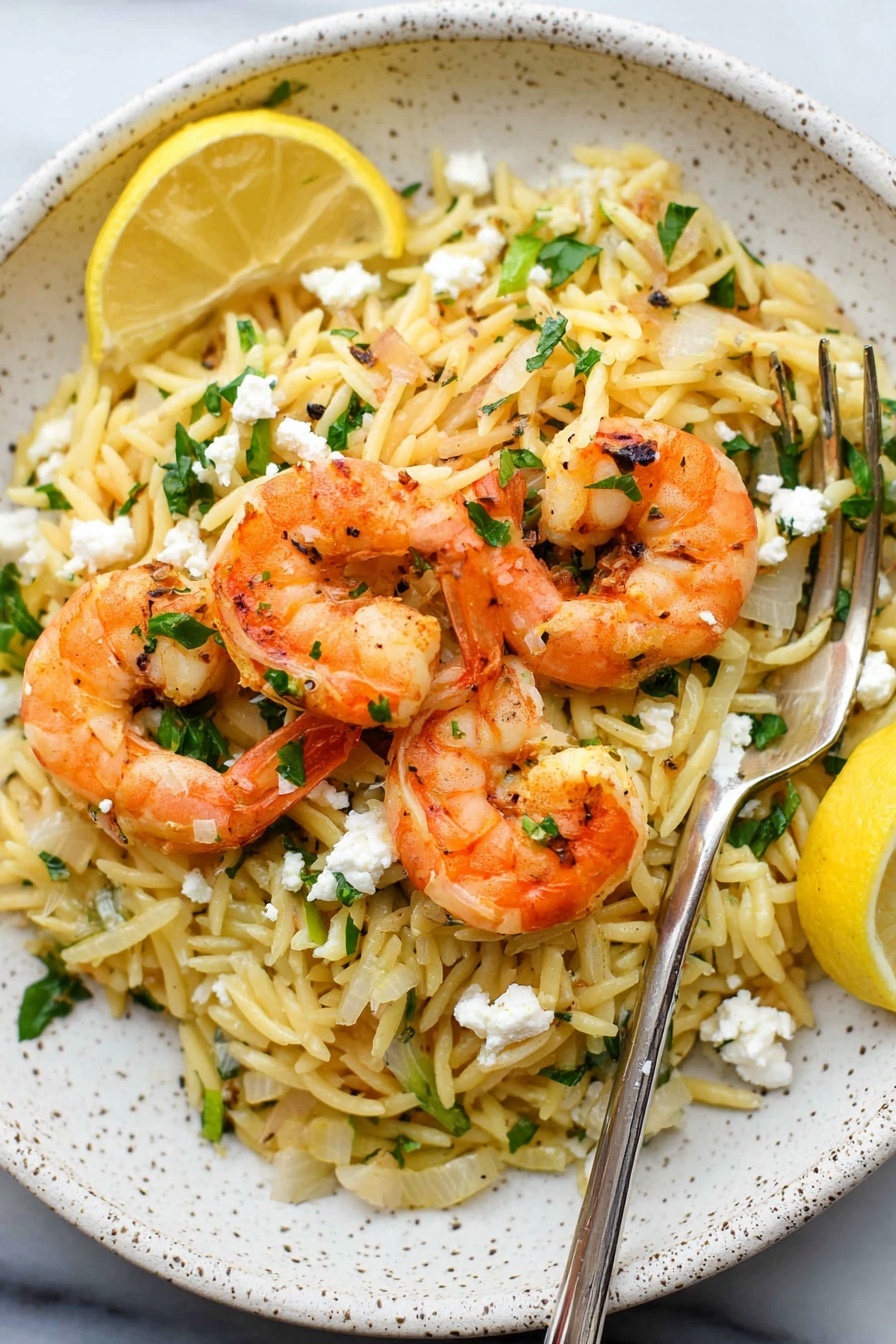 A white speckled plate holds a serving of light yellow pasta mixed with small chopped onions and green parsley pieces. On top of the pasta are four orange cooked shrimp with some slight grill marks. Small white crumbles of cheese are scattered over the shrimp and pasta. Two lemon wedges sit at the edge of the pasta, adding a bright yellow contrast. A silver fork rests on the plate's right side. The plate is placed on a white marbled surface. Photo taken with an iphone --ar 2:3 --v 7 - Shrimp and Feta Orzo, shrimp feta pasta, easy shrimp orzo, lemon shrimp pasta, quick seafood dinner
