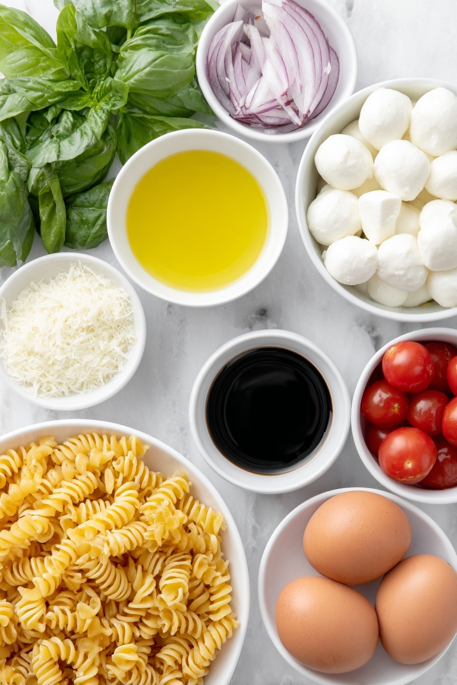 Flat lay of cavatappi pasta twisted spirals, a small white bowl of extra-virgin olive oil glistening, a small white bowl of fresh lemon juice pale yellow, a small white bowl of dark balsamic vinegar, a small white bowl of finely grated pecorino cheese light off-white, a few garlic cloves whole and peeled, a small pile of coarse sea salt crystals, a few twists of freshly ground black pepper, a handful of halved bright red cherry tomatoes, several halved mini mozzarella balls pure white and smooth, thinly sliced rings of red onion vibrant purple, a heaping handful of fresh basil leaves deep green torn and whole, several whole brown eggs with clean shells placed nearby, all arranged symmetrically on simple white ceramic bowls and plates, placed on a clean white marble surface, soft natural light, photo taken with an iPhone, professional food photography style, fresh ingredients, white ceramic bowls, no bottles, no duplicates, no utensils, no packaging --ar 2:3 --v 7 --p m7354615311229779997 - Caprese Pasta Salad with Cherry Tomatoes, cherry tomato pasta salad, summer pasta salad, easy Caprese pasta recipe, fresh Italian pasta salad