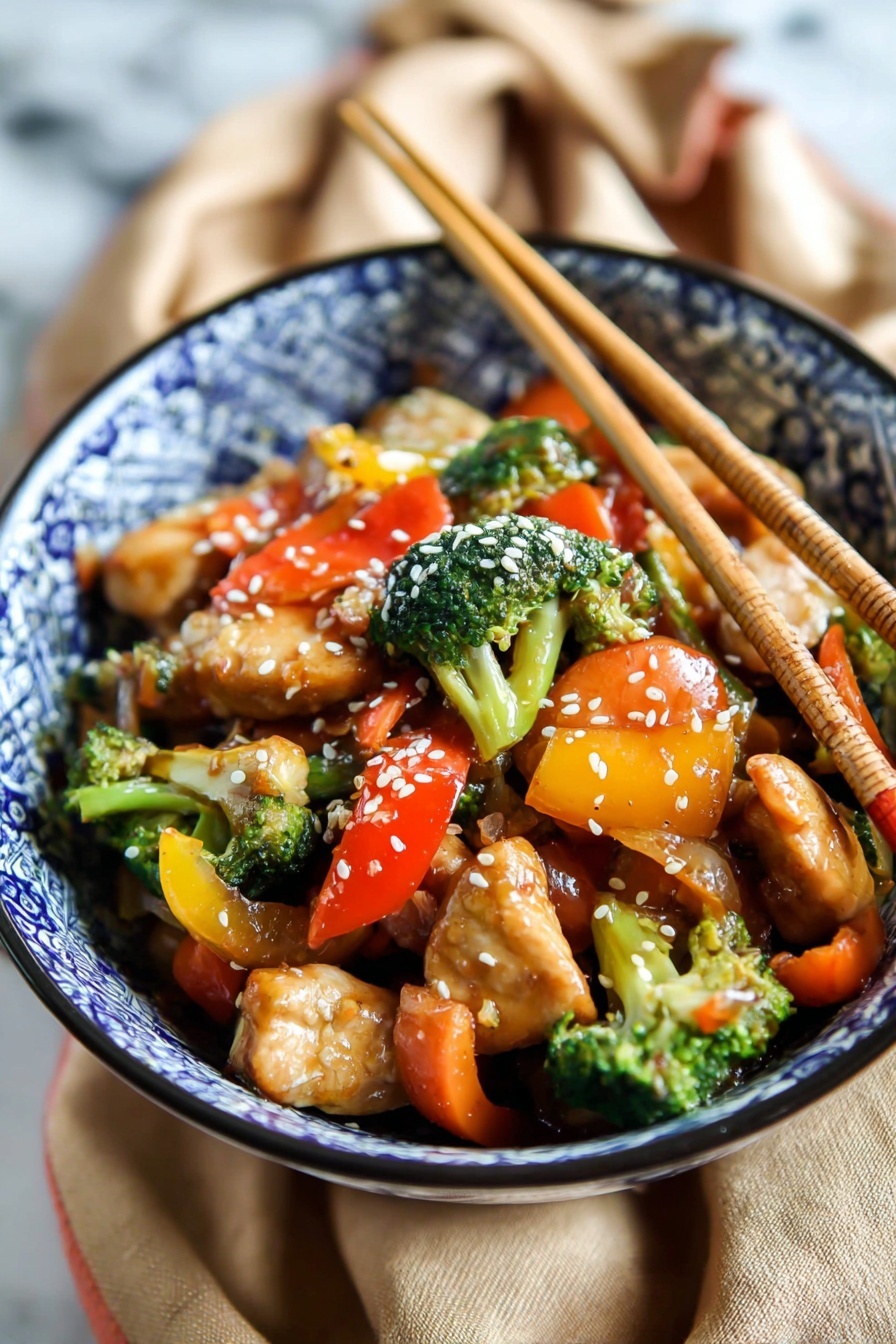 A bowl with blue and white patterned design holds a colorful stir-fry dish. The bottom layer is juicy, light brown pieces of chicken. Mixed with the chicken are bright green broccoli florets, orange carrot slices, and chunks of red and yellow bell peppers. The vegetables appear fresh and slightly glossy with sauce. White sesame seeds sprinkled on top add texture. Two wooden chopsticks stand upright in the bowl. The bowl sits on a tan fabric on a white marbled surface. Photo taken with an iphone --ar 2:3 --v 7 - Quick Chicken Stir Fry with Veggies, healthy chicken stir fry recipe, fast veggie stir fry, easy chicken stir fry dinner, quick stir fry dinner