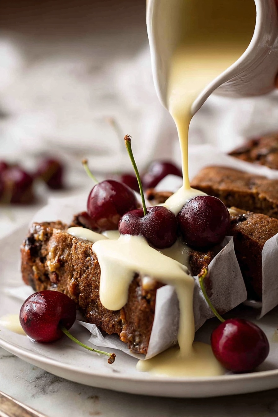 A white plate holds a dark brown cake with a rough texture, sliced into pieces and wrapped in white paper secured with small pins. The cake is topped with several shiny, deep red cherries with green stems. A creamy pale yellow sauce is being poured over the cake from a white pitcher, covering parts of the cake and dripping onto the plate. The white marbled surface beneath contrasts softly with the rich colors of the cake and cherries. Woman's hand is holding the pitcher. Photo taken with an iphone --ar 2:3 --v 7 - Easy Moist Christmas Fruit Cake, Christmas fruit cake recipe, moist holiday cake, simple Christmas cake, rich fruit cake