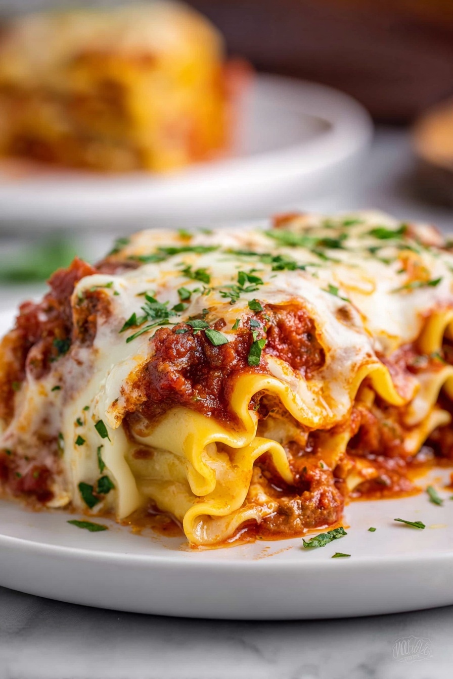 The image shows a close-up of a rolled lasagna piece on a white plate, placed over a white marbled surface. The lasagna has many wavy layers of soft, yellow pasta filled with a thick red meat sauce and melted cheese. The top is covered with a layer of creamy white melted cheese that is slightly browned in spots, sprinkled with bright green chopped herbs. The sauce peeks through the edges of the pasta rolls, adding a rich red color to the dish. In the blurred background, part of another portion is visible on a similar white plate. Photo taken with an iphone --ar 2:3 --v 7 - Cheesy Beef Lasagna Roll Ups, cheesy beef lasagna roll-ups, beef lasagna roll ups recipe, lasagna roll ups with beef and cheese, hearty baked lasagna roll-ups