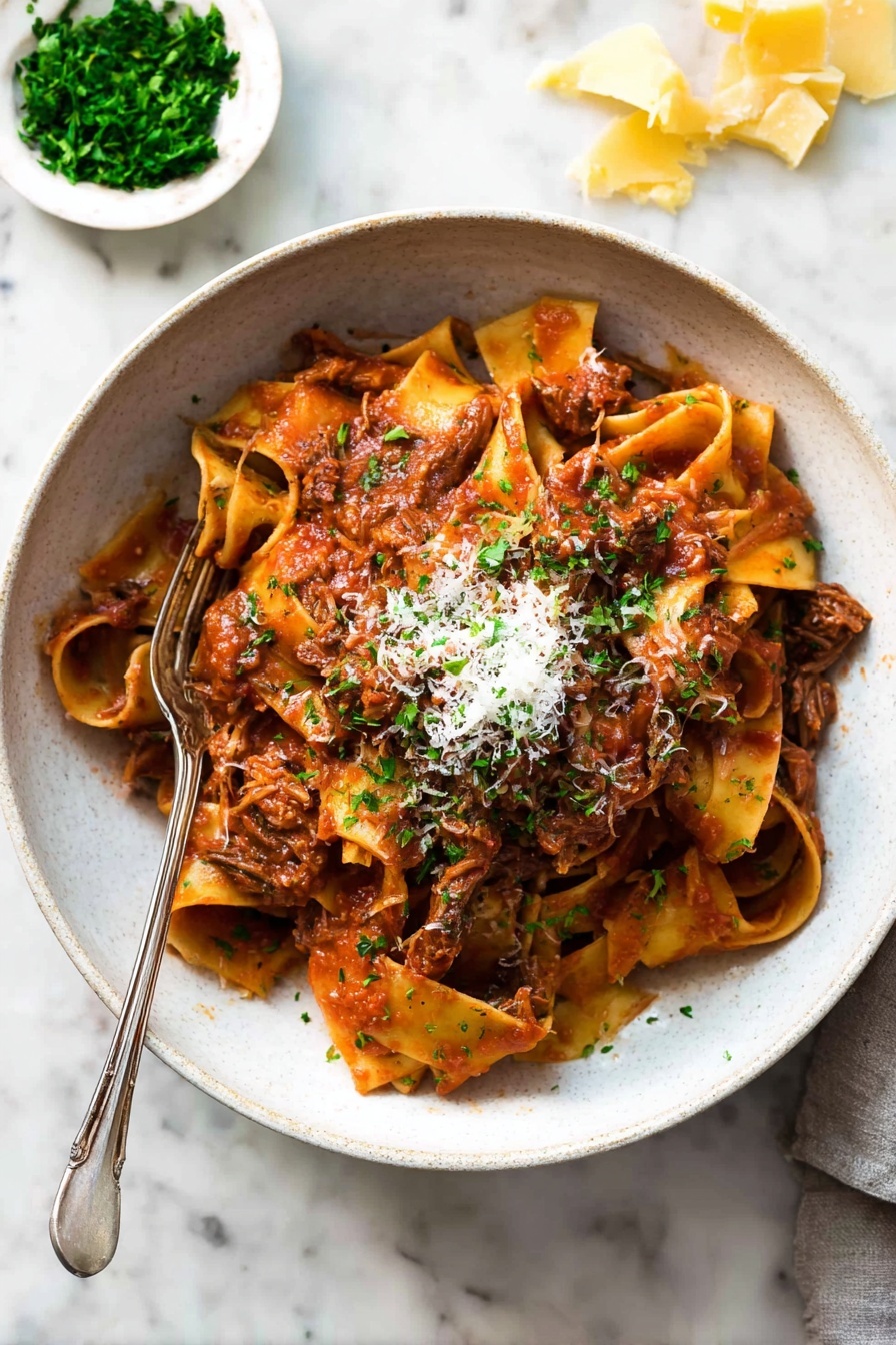 A bowl filled with wide, soft pasta noodles layered with shredded brown meat mixed in a thick red tomato sauce. The pasta sits in a white bowl, topped with a small pile of grated light cheese and finely chopped green herbs. A fork is placed inside the bowl, resting on the pasta. The background shows a white marbled surface with a small white dish holding chopped green herbs and pieces of yellow cheese scattered nearby. Photo taken with an iphone --ar 2:3 --v 7 - Slow Cooked Beef Ragu Pasta, Beef Ragu Pasta, Easy Beef Ragu, Tender Beef Pasta, Comforting Pasta Recipes