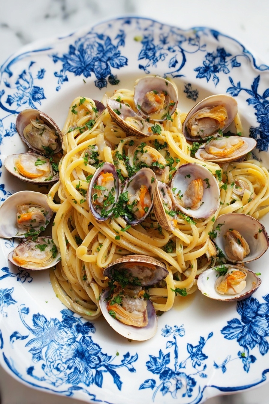 A white plate with blue floral patterns holds a serving of spaghetti pasta as the bottom layer, light yellow and slightly shiny. On top of the pasta, there are many open clam shells with light brown and white inner textures and soft orange clam meat inside. The dish is sprinkled with finely chopped green parsley evenly over the pasta and clams. The plate is placed on a white marbled surface. photo taken with an iphone --ar 2:3 --v 7 - Linguine with Clams and Garlic, seafood pasta recipes, easy Italian pasta, quick clam pasta, gourmet seafood dinner