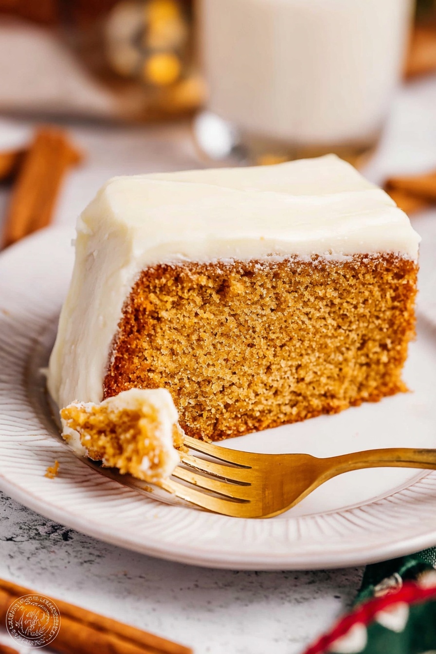 The image shows a slice of thick, light brown cake with a moist texture, topped with a thick white frosting layer covering the top and sides. The slice is placed on a white plate with a subtle embossed design along the edge. A golden fork is cutting into the cake slice. The background has a white marbled texture with blurred elements including cinnamon sticks and a glass cup. Warm lighting highlights the soft texture of the frosting and the crumb of the cake. Photo taken with an iphone --ar 2:3 --v 7 - Eggnog Bread with Rum Glaze, Eggnog Christmas Bread, Festive Eggnog Bread, Holiday Eggnog Loaf, Rum Glazed Eggnog Dessert