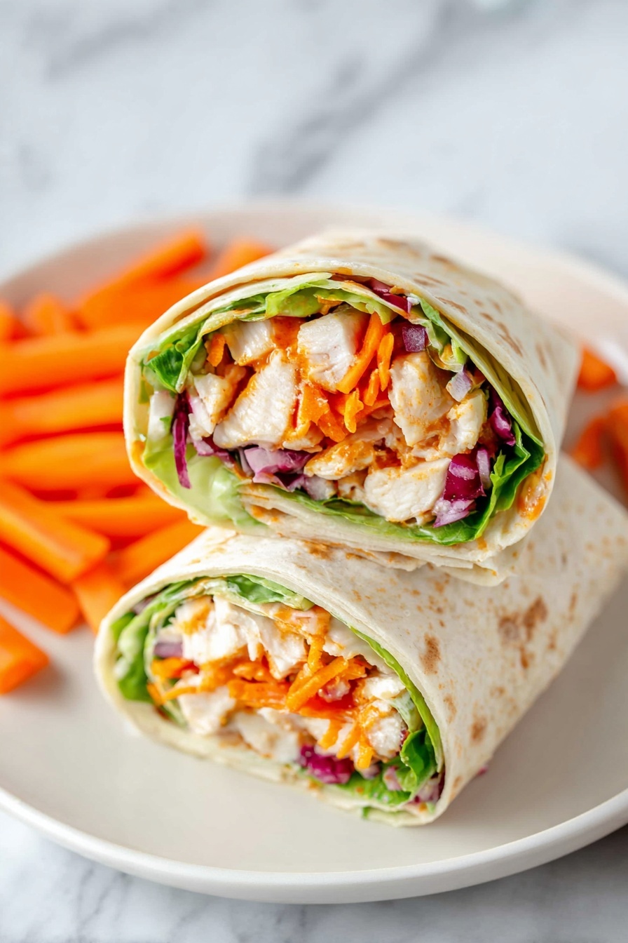 Two wrap halves are placed side by side on a white plate with small orange carrot sticks scattered around. Each wrap shows clear layers starting with a light tortilla on the outside, next a layer of fresh green lettuce, followed by chunks of white chicken mixed with orange sauce, bright orange shredded carrots, and pieces of red onion. The wraps are cut cleanly, exposing the colorful and fresh filling inside. The plate is set on a white marbled surface. Photo taken with an iphone --ar 2:3 --v 7 - Buffalo Chicken Wraps, spicy chicken wraps, easy chicken wrap recipes, healthy buffalo chicken wrap, quick dinner ideas