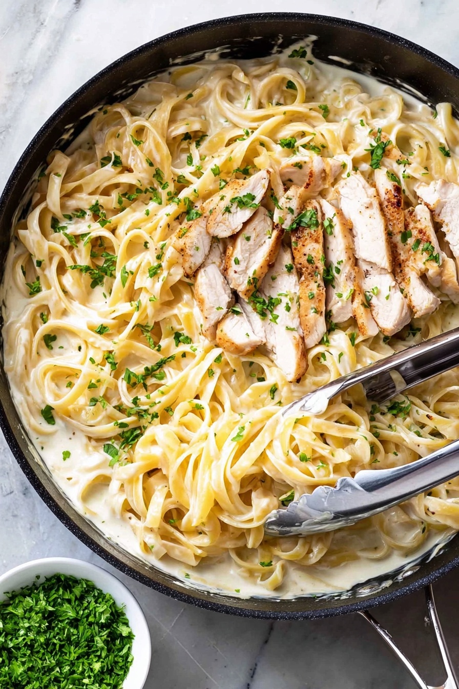 The image shows a black pan filled with creamy white sauce mixed with long, light yellow fettuccine noodles. On top of the noodles, there are several thin slices of cooked white meat with light brown edges. Small green parsley pieces are sprinkled all over the dish, adding a fresh touch. A pair of metal tongs rests inside the pan, slightly lifting some of the noodles. The pan is placed on a white marbled surface, and next to it is a small white bowl containing finely chopped green herbs. Photo taken with an iphone --ar 2:3 --v 7 - One-Pot Chicken Alfredo, Chicken Alfredo Pasta, Easy Creamy Alfredo, One-Pan Pasta Recipe, Simple Chicken Alfredo