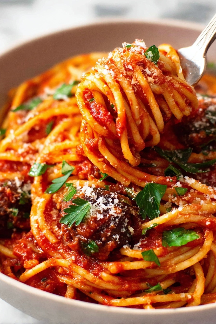 The image shows a close-up of a white bowl full of spaghetti pasta covered in bright red tomato sauce. The spaghetti strands are twisted around a silver fork that is lifting some noodles from the bowl, with a piece of dark brown meatball also on the fork. The pasta is sprinkled with white grated cheese and small green parsley leaves scattered on top, adding a fresh color touch. The background surface is a white marble texture, softly blurred to keep focus on the vibrant pasta dish. Photo taken with an iphone --ar 2:3 --v 7 - Eggplant Pasta alla Norma, Sicilian Eggplant Pasta, authentic Eggplant Pasta, easy Eggplant Pasta recipe, flavorful Italian pasta dishes