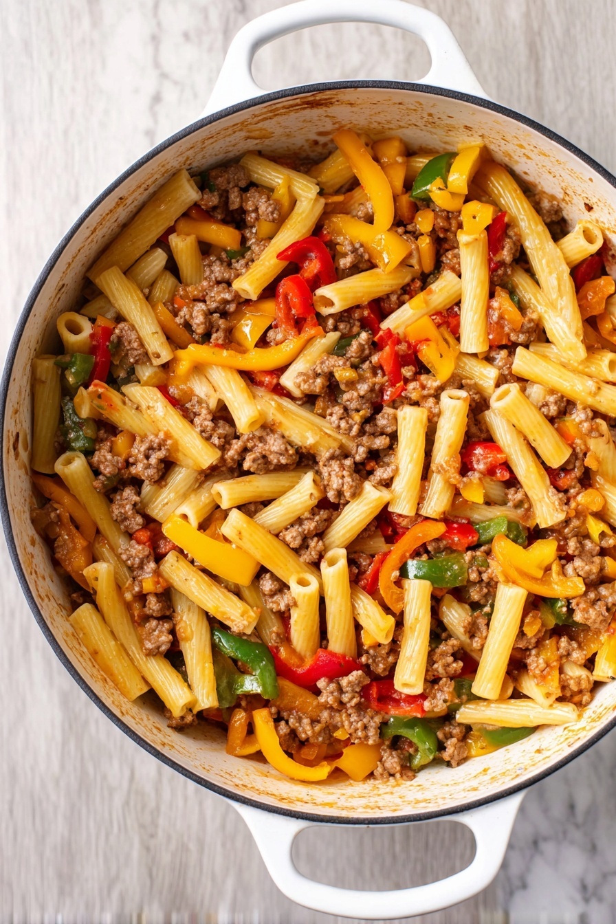 This image shows a white pot filled with a pasta dish featuring about three layers of ingredients. The bottom layer is short, tube-shaped pasta in a light yellow color. On top of this, there are chunks of cooked ground meat scattered throughout, appearing brown and crumbly. The top layer is mixed vegetables, including strips of red, yellow, and green bell peppers, adding bright colors and a fresh texture. The pot has white handles and sits on a white marbled surface. Photo taken with an iphone --ar 2:3 --v 7 - Italian Sausage and Peppers Pasta, Italian sausage pasta, sausage and peppers pasta, quick Italian pasta recipe, hearty sausage pasta