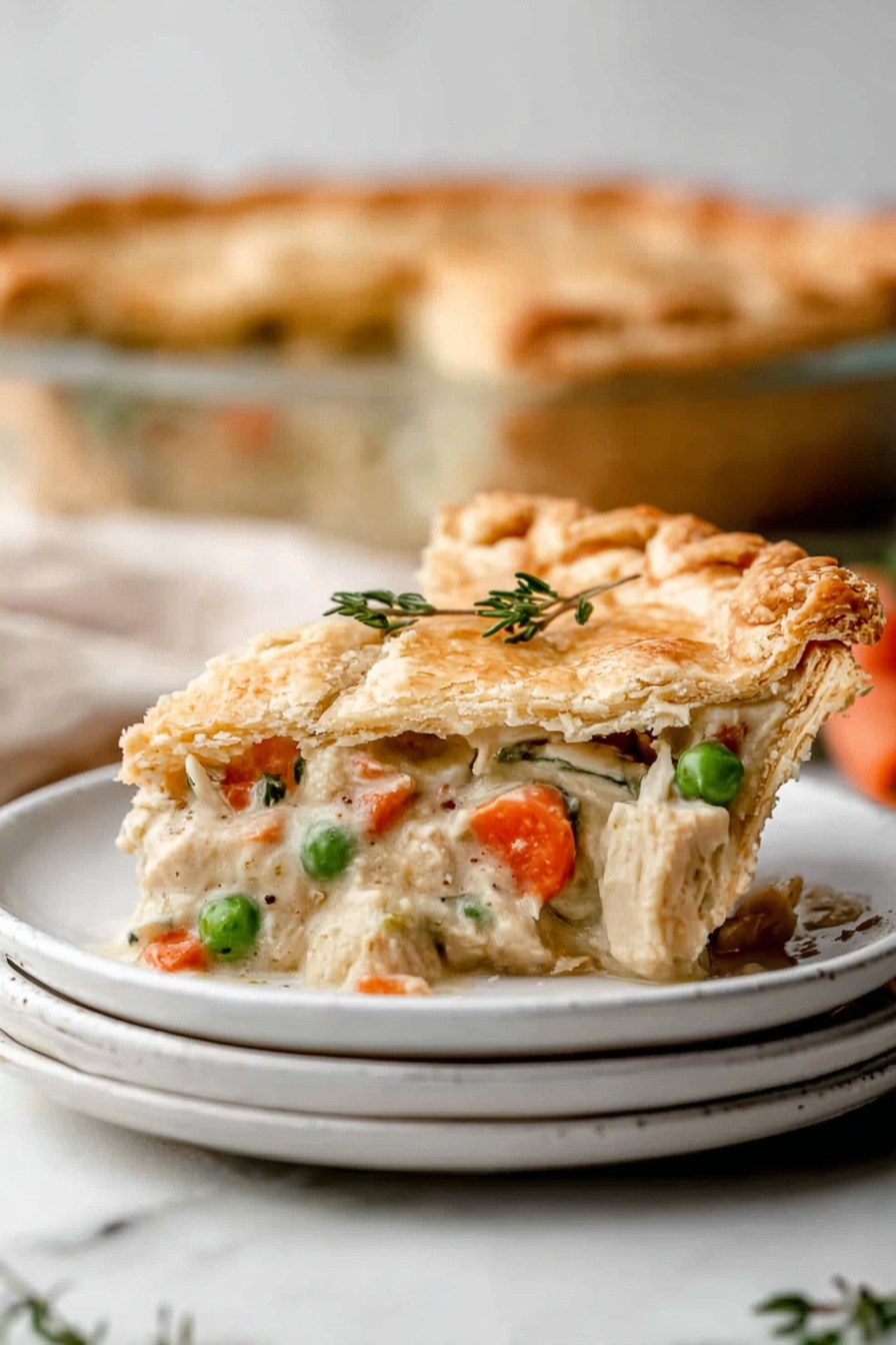 A slice of golden brown pie with a flaky crust sits stacked on two white plates with a creamy filling inside. The filling has soft pale chunks of white meat, bright orange carrot pieces, and green peas mixed in a thick light beige sauce. The crust edges are crimped and the top has a sprig of fresh green herb for decoration. In the blurry background, the rest of the pie is visible in a clear pie dish. The whole scene is set on a white marbled surface with a soft focus, showing warmth and homeliness. Photo taken with an iphone --ar 2:3 --v 7 - Best Chicken Pot Pie, chicken pot pie with flaky crust, hearty chicken and vegetable pie, comfort food chicken pie, homemade chicken pot pie