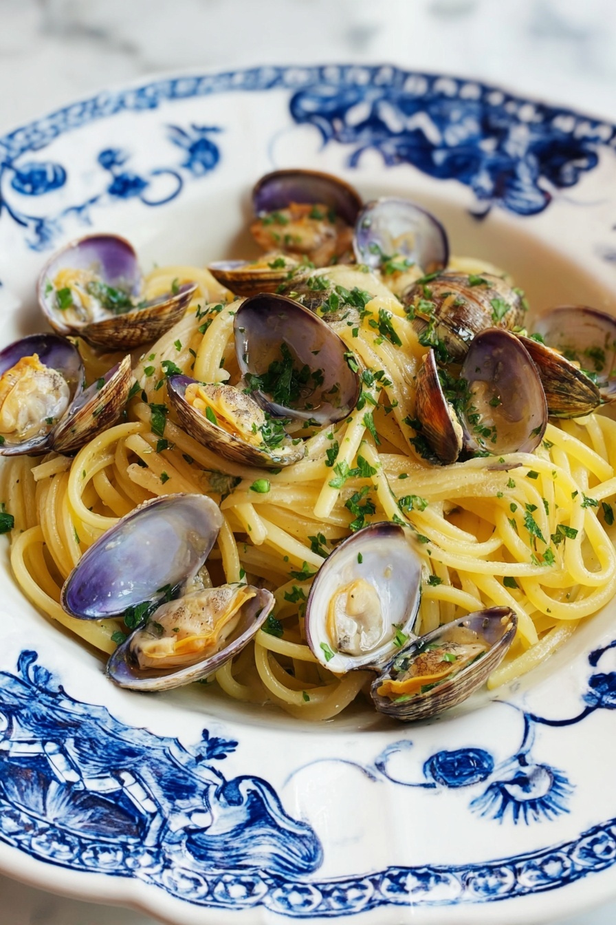A white plate with blue floral patterns holds a serving of spaghetti pasta layered at the bottom, showing a pale yellow color and smooth texture. Scattered over the pasta are many opened clam shells, beige and light brown with tender clam meat inside, slightly orange and shiny. Fresh chopped green herbs are sprinkled over the clams and pasta, adding a bright touch. The plate rests on a white marbled surface. photo taken with an iphone --ar 2:3 --v 7 - Linguine with Clams and Garlic, seafood pasta recipes, easy Italian pasta, quick clam pasta, gourmet seafood dinner