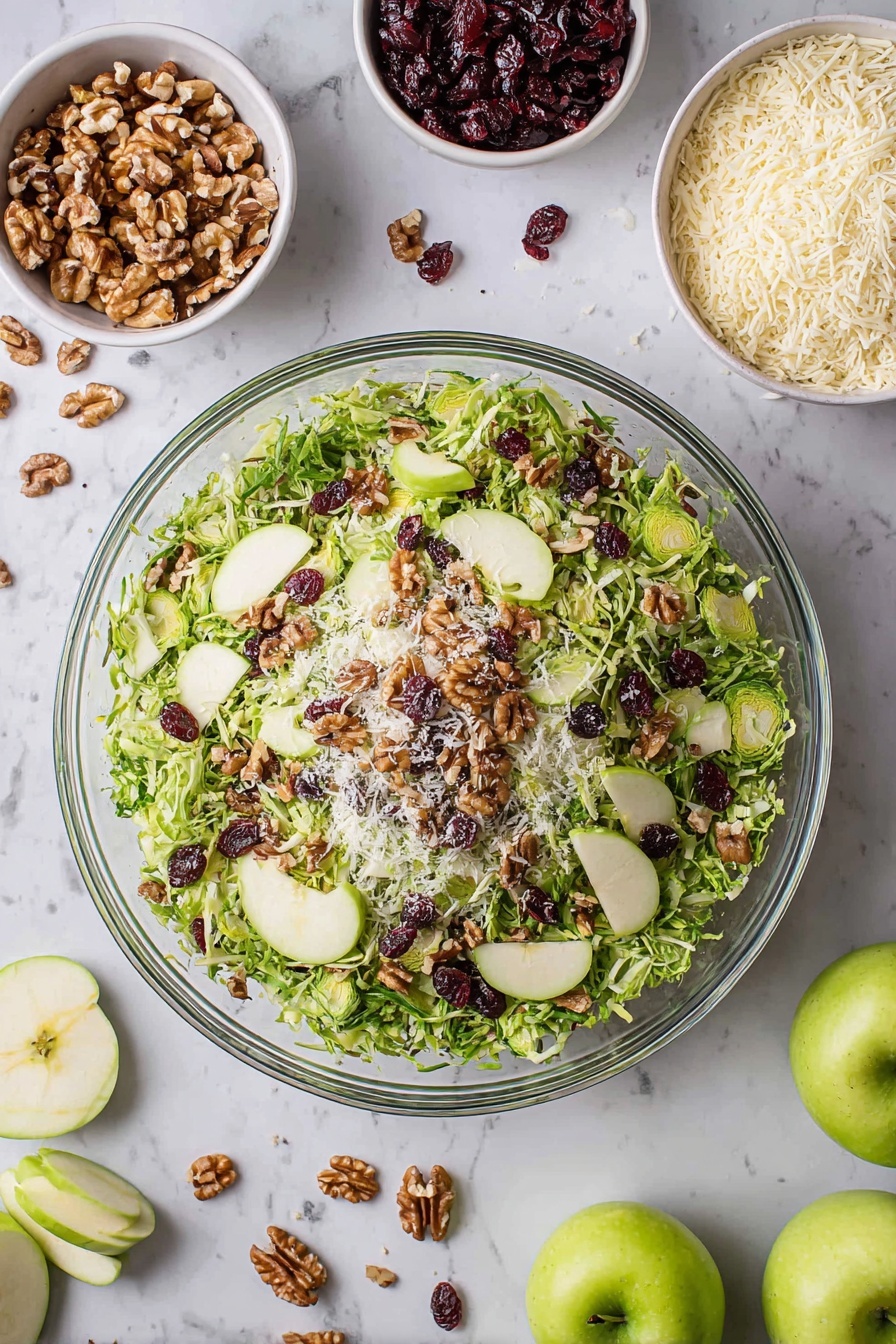 A large clear glass bowl filled with a fresh salad showing three layers: the bottom layer is shredded green Brussels sprouts, the middle layer is thinly sliced green apple slices placed evenly around, and the top layer is scattered walnut pieces, dark red dried cranberries, and small white grated cheese bits, all on a white marbled surface. Around the bowl are small white bowls containing walnuts, grated cheese, and dried cranberries, along with whole and sliced green apples and loose salad leaves scattered nearby. Photo taken with an iphone --ar 2:3 --v 7 - Brussels Sprouts Apple Cranberry Salad, seasonal healthy salad, holiday veggie salad, apple cranberry Brussels sprouts, festive winter salad