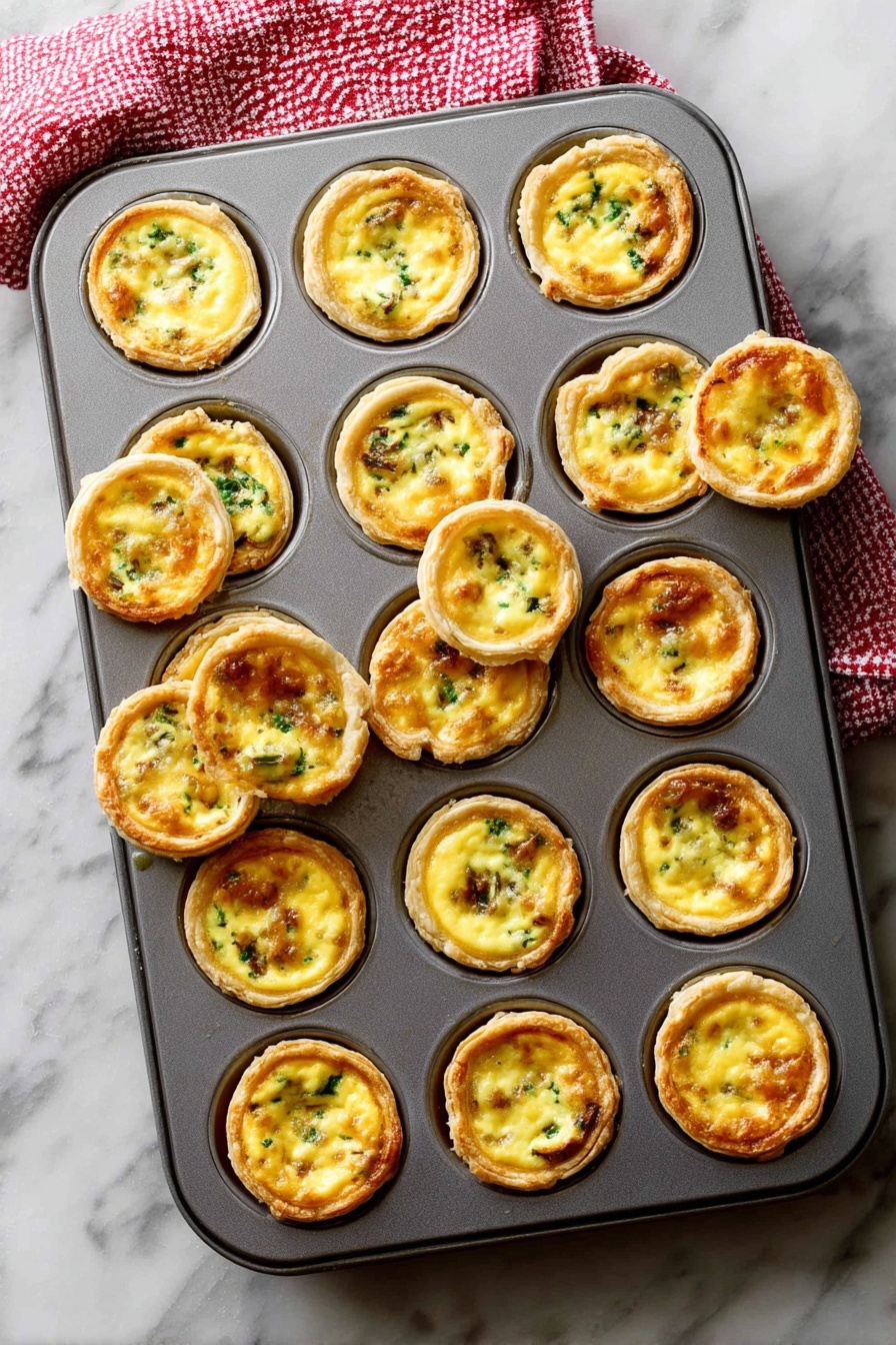 A gray metal muffin tray filled with 24 mini egg tarts, each tart consisting of a golden brown crust that forms a cup holding a smooth, creamy yellow egg filling mixed with small green and brown bits of vegetables or meat. Some tarts are slightly raised above the tray’s edge, showing a crisp outer layer, while a few are tilted or removed, revealing their round, flaky textured bottoms. The tray rests on a white marbled surface with a red and white checkered towel partly visible at the top left corner. Photo taken with an iphone --ar 2:3 --v 7 - Mini Quiches with Flaky Pie Crust, mini quiche recipe, savory mini quiches, easy brunch appetizers, bite-sized quiche ideas
