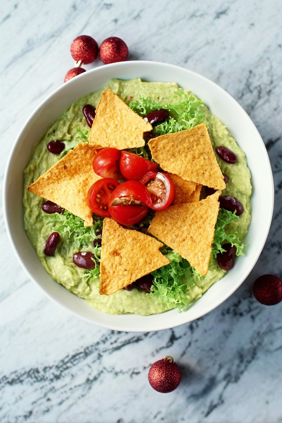 A white bowl filled with a creamy green guacamole base topped by several crispy golden tortilla chips placed in the center. Around the chips, there are bright red cherry tomato halves, fresh green lettuce leaves, and small dark red kidney beans scattered. The bowl is set on a white marbled surface. photo taken with an iphone --ar 2:3 --v 7 - Festive Guacamole with Pomegranate and Tomatoes, holiday guacamole, colorful holiday dip, quick festive appetizer, easy party guacamole