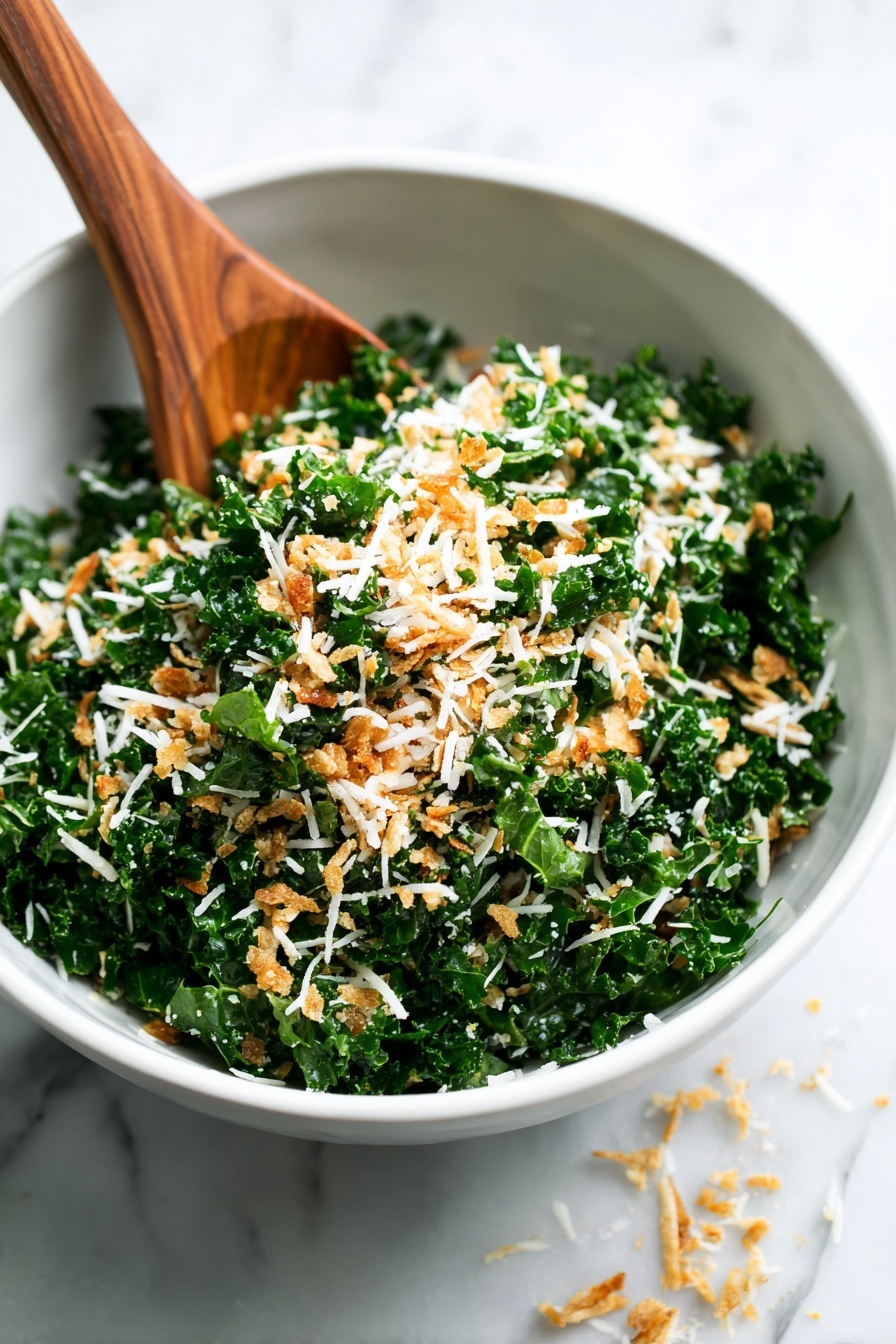 A close-up view of a white bowl filled with a green kale salad mixed with white shredded cheese and small golden brown crumb pieces, suggesting a mix of crunchy and soft textures. A wooden spoon is partially inside the bowl on the left side, stirring or resting above the salad. Some shredded cheese pieces are scattered on the white marbled surface around the bowl. The focus is sharp on the front part of the salad, while the background parts blur softly. photo taken with an iphone --ar 2:3 --v 7 - Crispy Parmesan Kale Salad, kale salad with parmesan, healthy kale salad recipes, crunchy kale salad, tangy kale salad with breadcrumbs