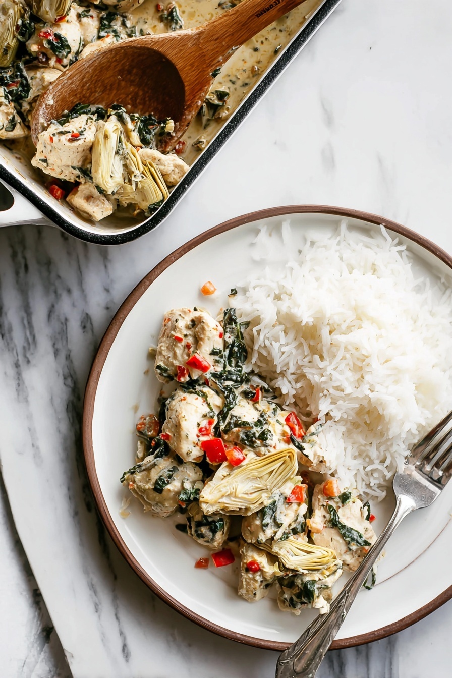 A white round plate shows two layers: on the left side, there are pieces of white cooked chicken mixed with dark green spinach leaves and small bright red bits of bell pepper, along with beige artichoke hearts placed among the chicken; on the right side, there is a mound of fluffy white rice with a silver fork resting on the right edge of the plate. Above the plate, a white rectangular baking dish with a dark rim holds more chicken mixture, and a wooden spoon is scooping some of the chicken and vegetables from the dish. All items are placed on a white marbled surface. photo taken with an iphone --ar 2:3 --v 7 - Creamy Spinach Artichoke Chicken Bake, spinach artichoke chicken casserole, easy chicken bake, healthy chicken dinner, cheesy chicken bake