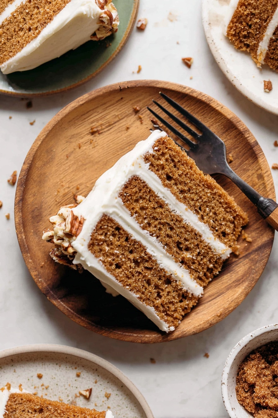 A slice of three-layer light brown cake with white cream frosting between each layer and around the edges sits on a round white plate with wood texture. The cake texture looks soft with small holes inside. There is a dark fork placed on the plate, partly holding the cake slice. Some small brown nut pieces are scattered on the white marbled surface under and around the plate. Part of another white plate with a similar cake slice is visible in the top right corner, while at the bottom right, there is a white bowl with a brown crumbly topping inside. Photo taken with an iphone --ar 2:3 --v 7 - Spice Cake with Brown Butter Frosting, cozy spice cake recipe, moist spice cake with cream cheese frosting, easy fall spice cake, homemade holiday spice cake