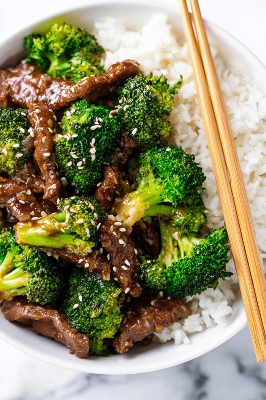 A white bowl filled with a bed of white rice as the bottom layer, topped with bright green broccoli florets and brown cooked meat strips covered in a glossy sauce. The meat and broccoli pieces are sprinkled with white sesame seeds. Two light brown chopsticks are resting on the right side of the bowl. The bowl sits on a white marbled surface. photo taken with an iphone --ar 2:3 --v 7 - Crockpot Beef and Broccoli Stir Fry, easy crockpot beef stir fry, slow cooker broccoli beef, healthy slow cooker dinner, homemade beef stir fry