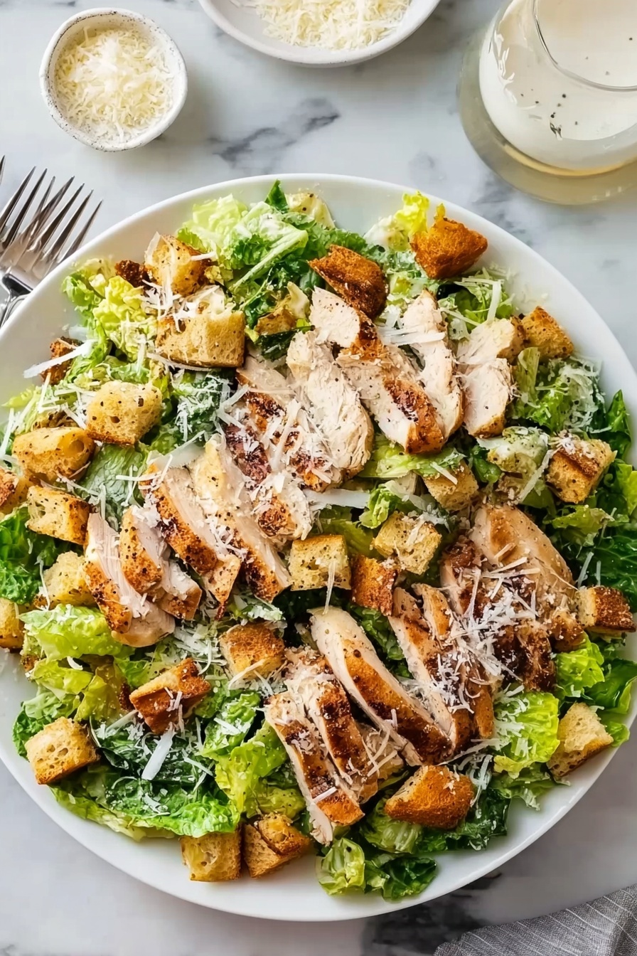 A large white plate holds a fresh salad with several layers: the bottom layer is a mix of crisp green romaine lettuce leaves. On top, there are many grilled chicken slices, light brown with dark grill marks, spread evenly over the lettuce. Scattered among the chicken are golden brown, crunchy croutons. The salad is lightly sprinkled with grated white cheese that adds a delicate touch all over. The plate is placed on a white marbled surface, with a fork visible on the left side and two small white bowls, one filled with more grated cheese and the other with a creamy dressing, near the top right corner. Photo taken with an iphone --ar 2:3 --v 7 - Best Chicken Caesar Salad with Homemade Croutons, Chicken Caesar Salad, Homemade Croutons Recipe, Grilled Chicken Salad, Easy Caesar Salad