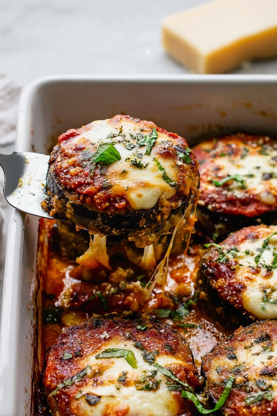 The image shows a white baking dish filled with several round pieces of eggplant Parmesan. Each piece has three visible layers: a dark brown crispy eggplant slice at the bottom, a middle layer of red tomato sauce, and a top layer of melted, light golden cheese with some browned spots. Small green basil leaves and chopped herbs are sprinkled over the cheese. One piece is being lifted out of the dish with a silver spatula, and strings of melted cheese stretch between the piece and the dish. The dish is set on a white marbled surface with a wedge of Parmesan cheese blurred in the background. photo taken with an iphone --ar 2:3 --v 7 - Eggplant Parmesan Quick and Easy, Eggplant Parmesan Recipe, Homemade Eggplant Parmesan, Baked Eggplant Parmesan, Vegetarian Eggplant Dish