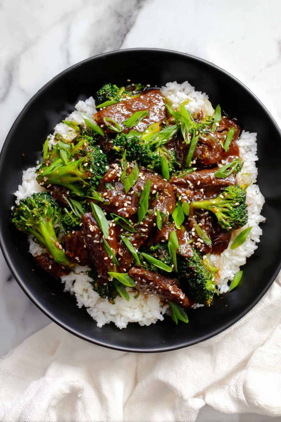 A black bowl holds a bed of white, fluffy rice as the base layer, covered with a second layer of glossy, dark brown beef slices mixed with bright green broccoli florets. The beef and broccoli are coated in a shiny sauce that makes the dish look rich and moist. Scattered on top are fresh, bright green sliced scallions and tiny beige sesame seeds, adding texture and color contrast. The bowl sits on a white marbled surface with a white cloth napkin casually draped nearby. photo taken with an iphone --ar 2:3 --v 7 - Garlic Beef with Broccoli Stir-Fry, Beef and Broccoli Stir-Fry, Easy Chinese Stir-Fry, Healthy Beef Stir-Fry Recipe, Quick Weeknight Dinner
