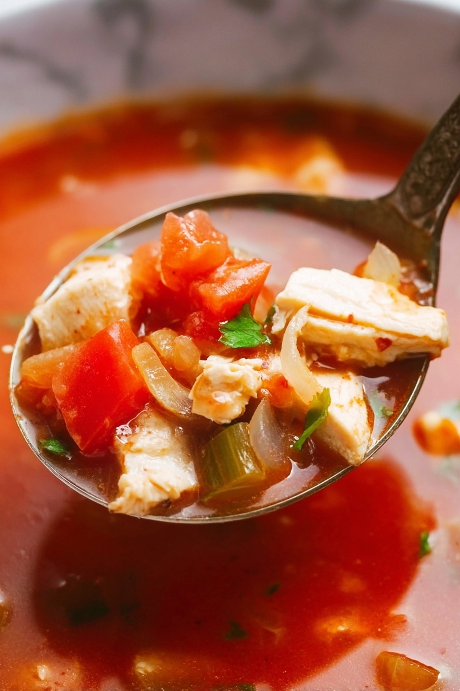 A close-up view of a spoon filled with a tomato-based soup showing layers of light beige chicken pieces, bright red tomato chunks, translucent pale yellow onions, and small green herb bits in a rich red broth. The soup's liquid looks smooth and glossy, surrounding the solid ingredients with a warm, comforting shine. Inside the spoon, the layers are densely packed, with diced chicken pieces on top and vegetables evenly scattered around. The background features the same white marbled texture, adding a clean look to the image. photo taken with an iphone --ar 2:3 --v 7 - Cilantro Salmon Tomato Soup, healthy salmon soup, quick salmon soup recipe, flavorful salmon tomato broth, easy one-pot salmon soup