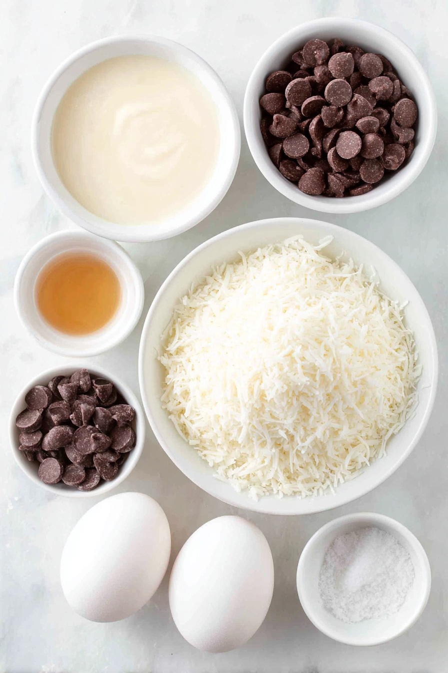 Flat lay of a small mound of fresh sweetened shredded coconut, a small white bowl filled with thick sweetened condensed milk, a few drops of golden vanilla extract in a tiny white bowl, a pinch of coarse salt in another small white bowl, two large whole white eggs with clean shells, and a small white bowl of glossy semi-sweet chocolate chips, all arranged in perfect symmetry on a clean white marble surface, soft natural light, photo taken with an iPhone, professional food photography style, fresh ingredients, white ceramic bowls, no bottles, no duplicates, no utensils, no packaging --ar 2:3 --v 7 --p m7354615311229779997 - Chocolate-Dipped Coconut Macaroons, coconut macaroons recipe, easy coconut cookies, chocolate-coated macaroons, chewy coconut treats