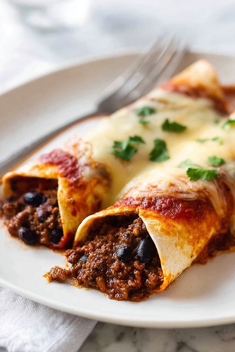 Two rolled enchiladas sit side by side on a white plate, placed on a white marbled surface. Each enchilada has a soft, golden-brown tortilla filled with dark, crumbly cooked ground meat mixed with small black beans visible inside. The top layer of the tortillas is covered in a rich red sauce and melted white cheese, which has a slightly stretchy texture. Small green cilantro leaves are scattered over the top, adding a fresh pop of color. The edges of the tortillas are slightly browned from baking. In the background, the silver fork lies blurred on the plate. Photo taken with an iphone --ar 2:3 --v 7 - Beef Enchiladas, Beef Enchiladas Recipe, Homemade Beef Enchiladas, Easy Beef Enchiladas, Beef Enchiladas Dinner
