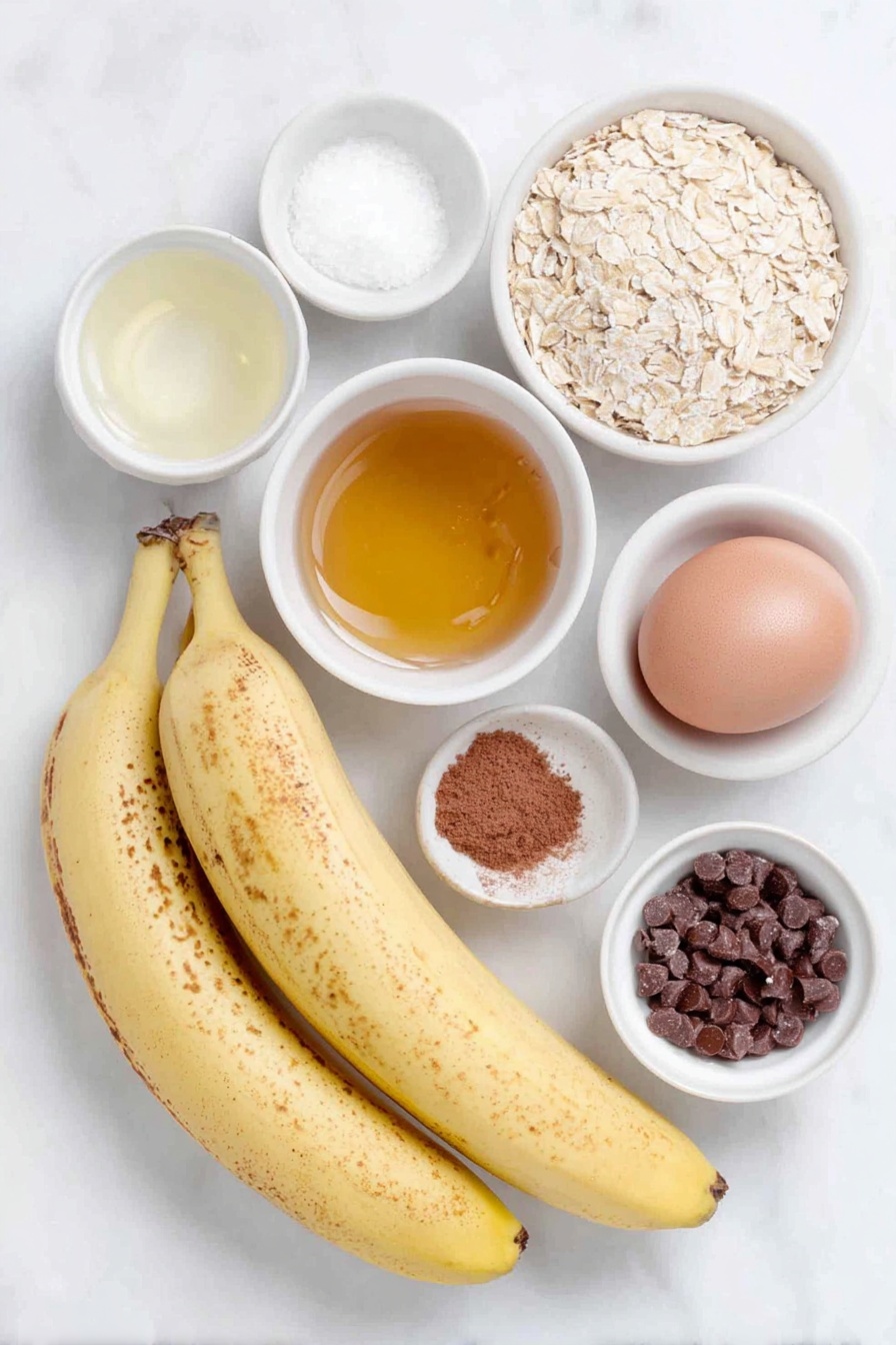 Flat lay of three ripe yellow bananas with some brown spots, a small white ceramic bowl of golden honey, one whole uncracked brown egg, a small white ceramic bowl of translucent vanilla extract, a small white ceramic bowl filled with light beige quick cooking oats, a small white ceramic bowl of fine ground cinnamon powder, a small white ceramic bowl of fine sea salt crystals, a small white ceramic bowl filled with semi-sweet chocolate chips, all arranged symmetrically and balanced on a clean white marble surface, soft natural light, photo taken with an iPhone, professional food photography style, fresh ingredients, white ceramic bowls, no bottles, no duplicates, no utensils, no packaging --ar 2:3 --v 7 --p m7354615311229779997 - Banana Oatmeal Cookies, healthy banana cookies, easy oatmeal cookies, gluten-free banana treats, soft cinnamon cookies